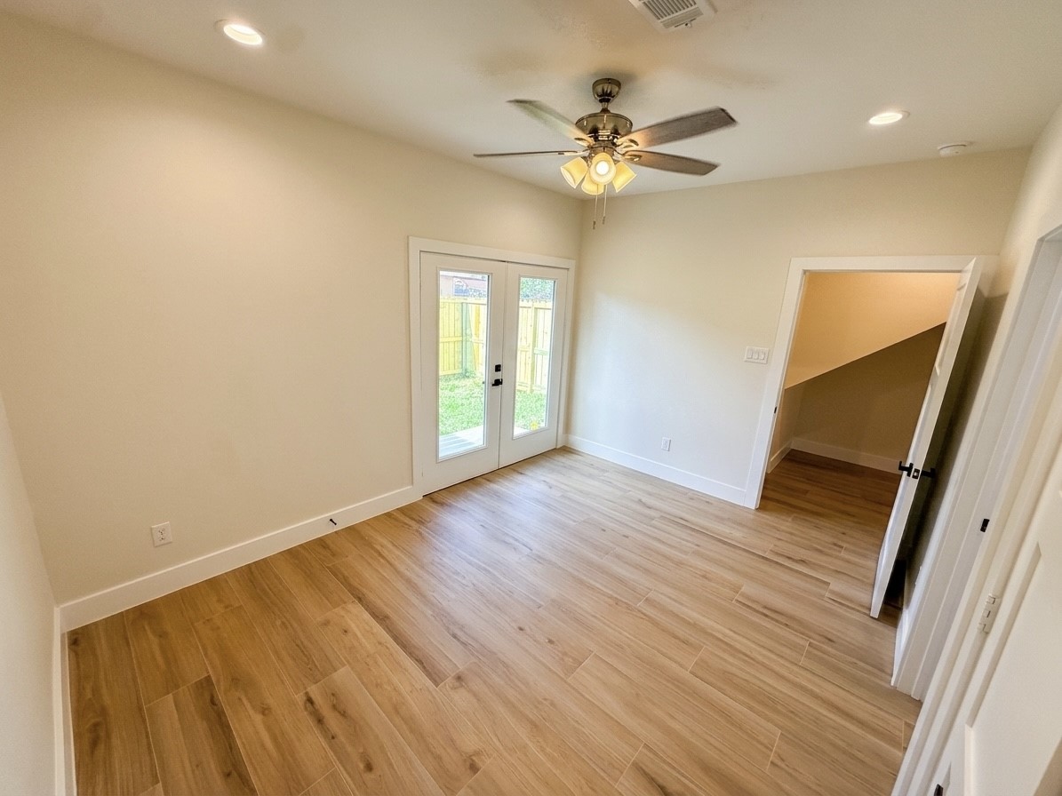 Bright and inviting room with porcelain flooring, and double doors opening to a private backyard, perfect for relaxation or entertaining.