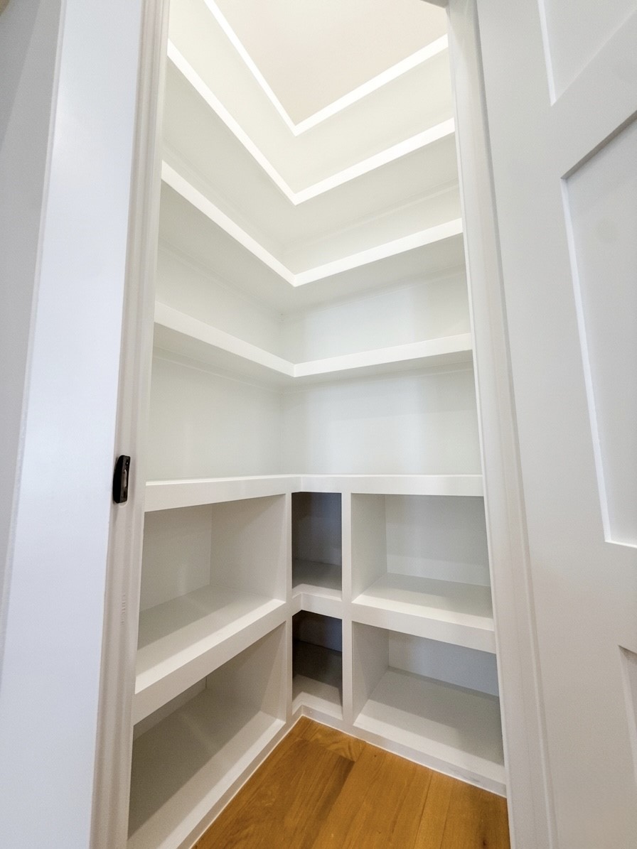 Spacious walk-in pantry with custom-built shelving, perfect for organized storage.