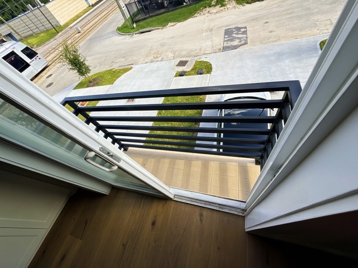 Charming balcony with sleek black railings offers a cozy outdoor space overlooking street.