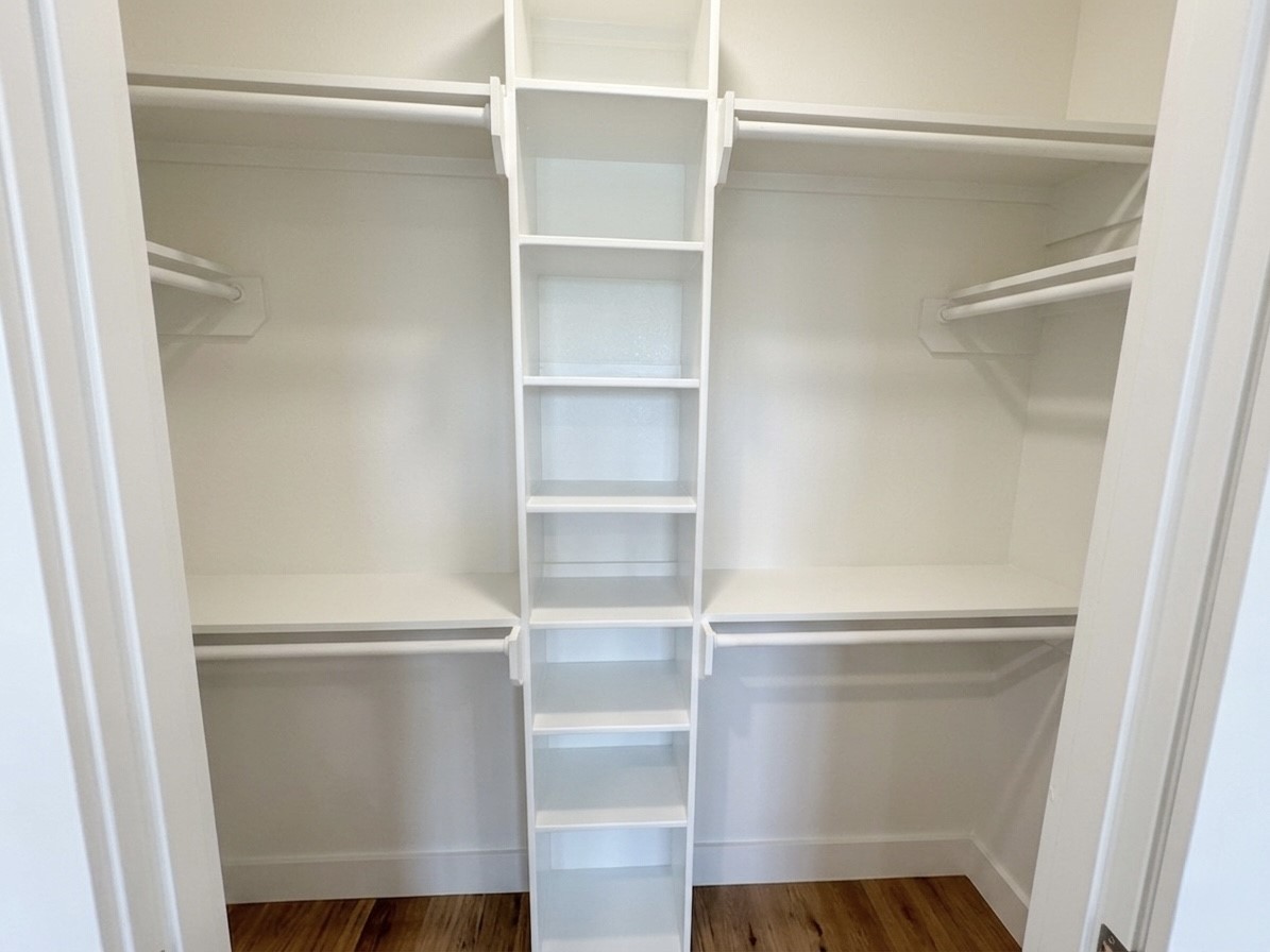 Spacious walk-in closet featuring ample shelving and dual hanging rods for organized storage.
