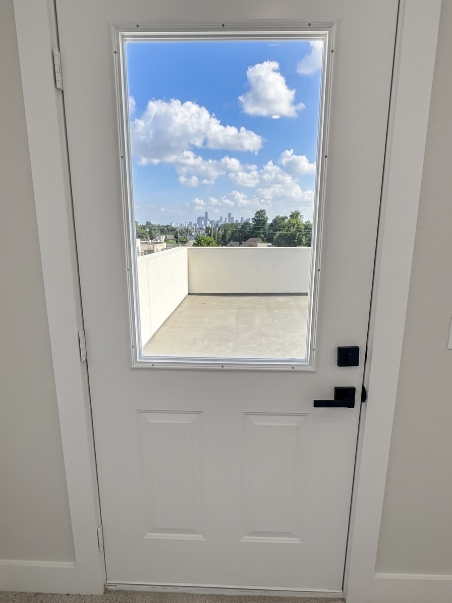Step through a sleek door onto a spacious terrace, offering stunning skyline views under a bright blue sky.