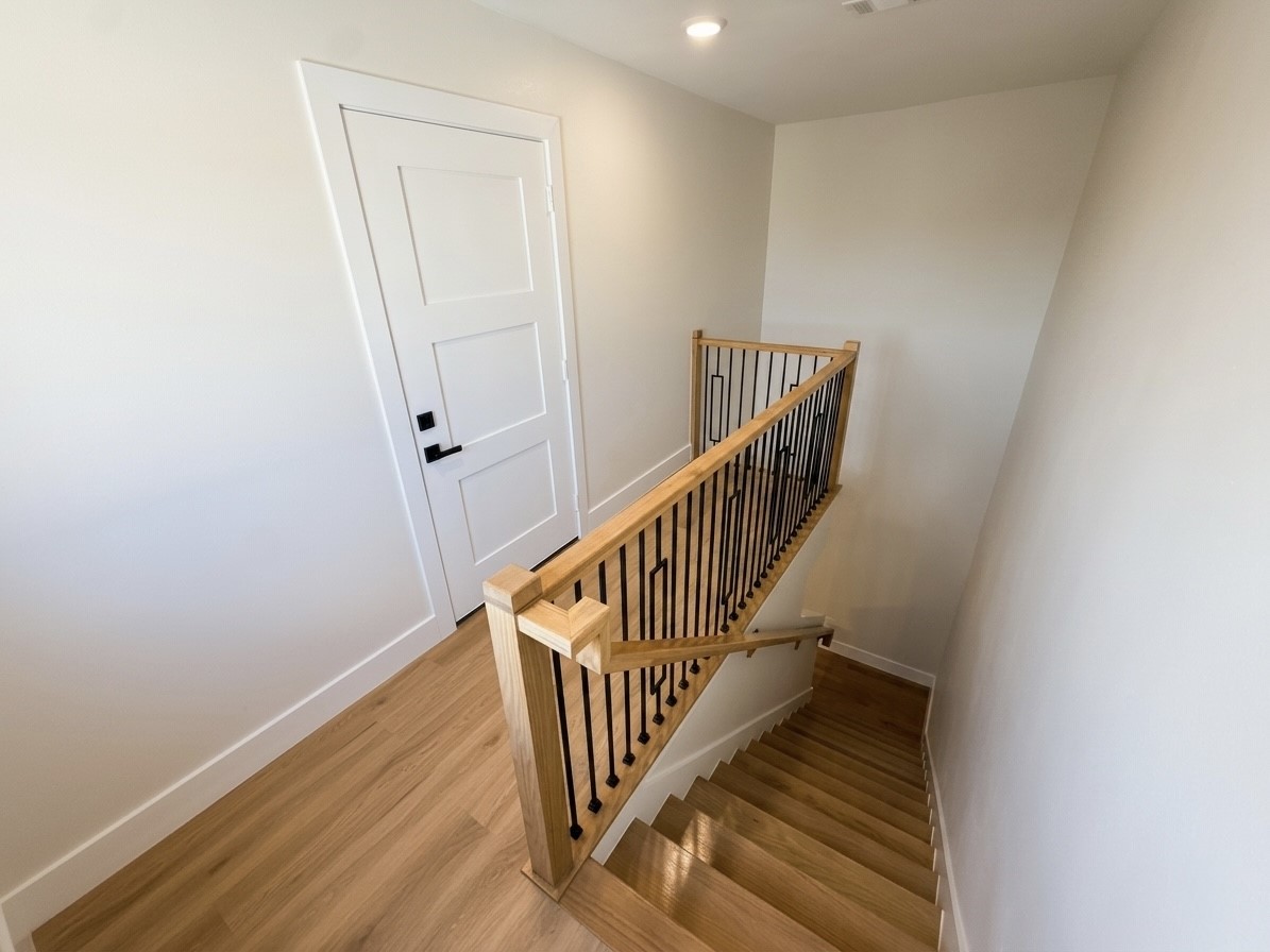 Bright and inviting staircase with elegant wooden railings leads to a modern interior door, enhancing the home's contemporary design.