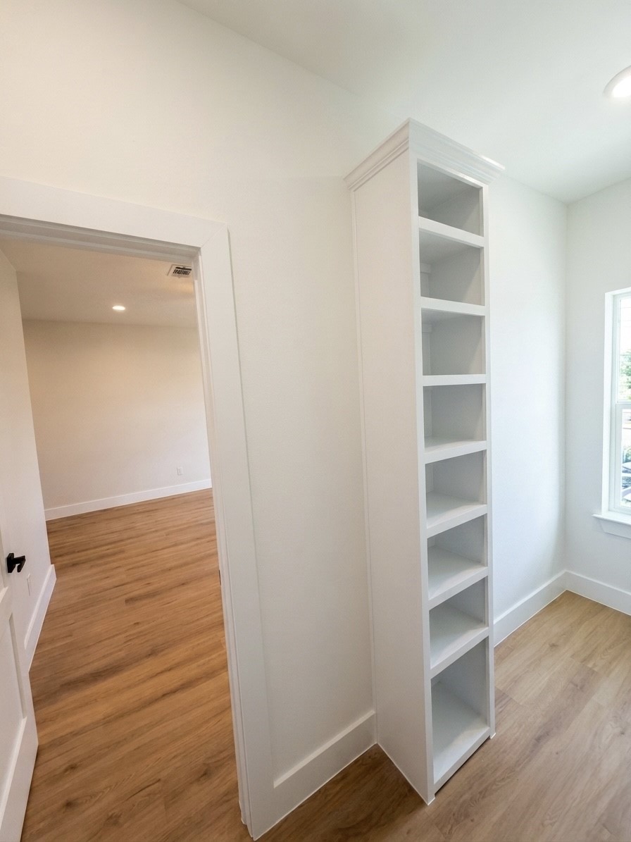 Bright room featuring sleek engineered wooden floors and a slim built-in shelving unit, ideal for display or storage.