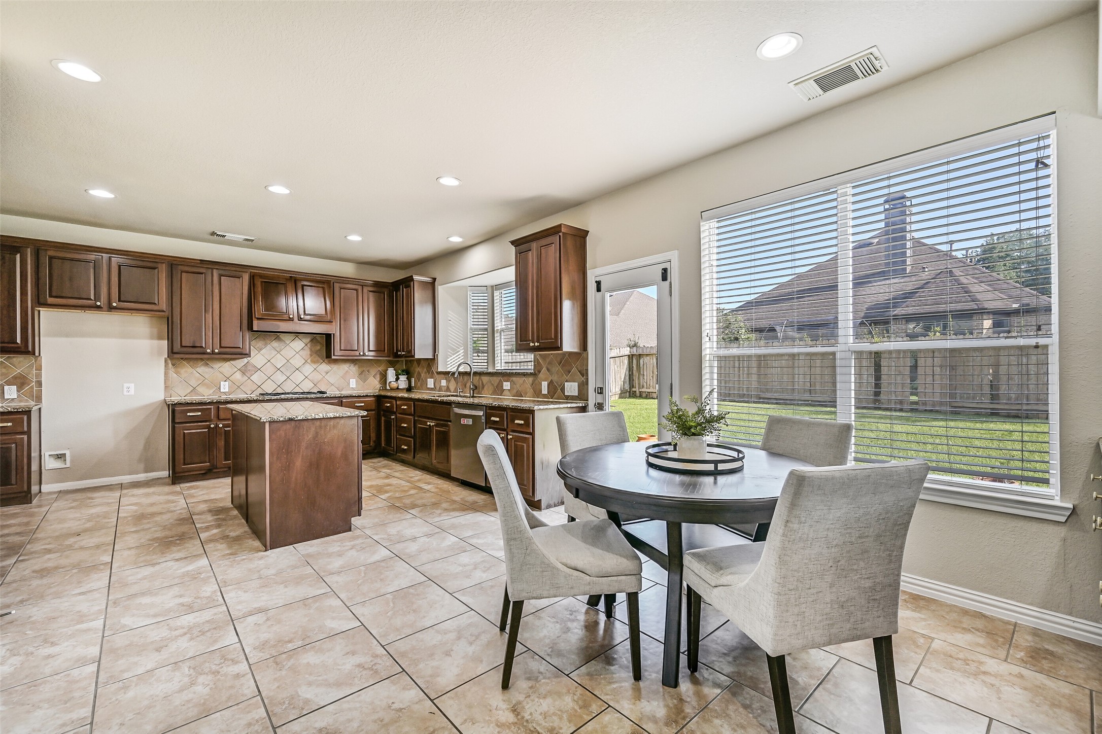 Just beyond the kitchen, the sunlit breakfast room offers a casual dining space wrapped in windows overlooking the backyard. A built-in granite-topped buffet provides extra storage and serving space, making it equally convenient for everyday meals and entertaining guests.