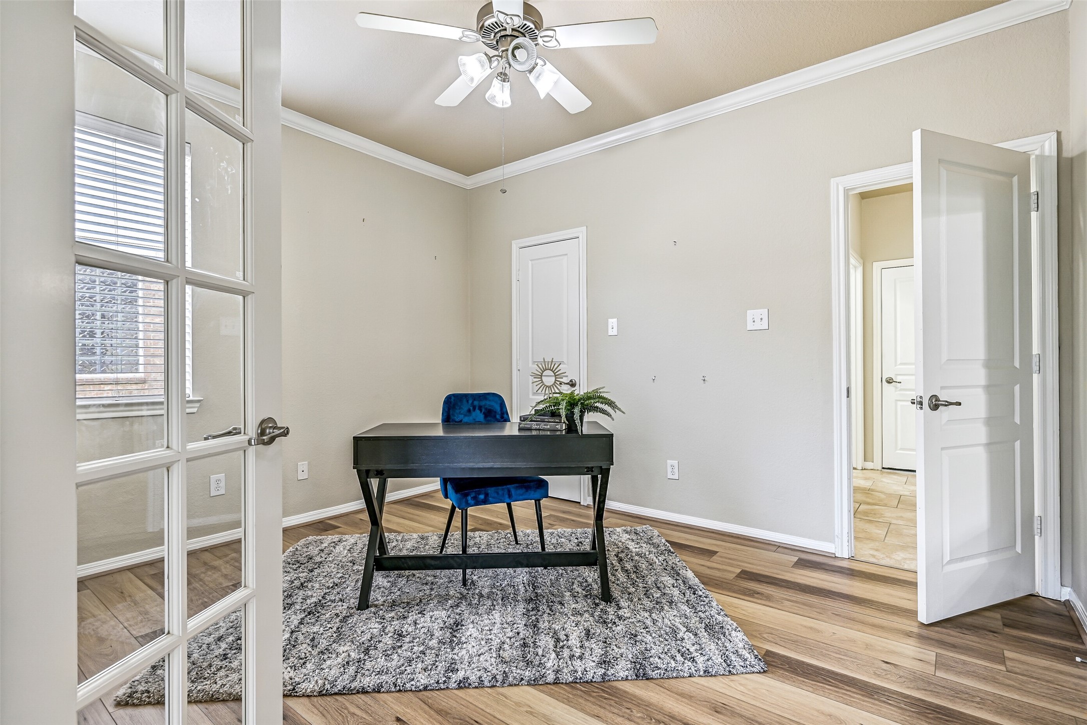 French doors open to a private first-floor study featuring fresh neutral paint, crown molding, a lighted ceiling fan, and newly installed luxury vinyl plank flooring. Complete with a closet and convenient access to a nearby full bathroom, this versatile room can easily serve as a home office, playroom, guest retreat, or even a fifth bedroom if needed.