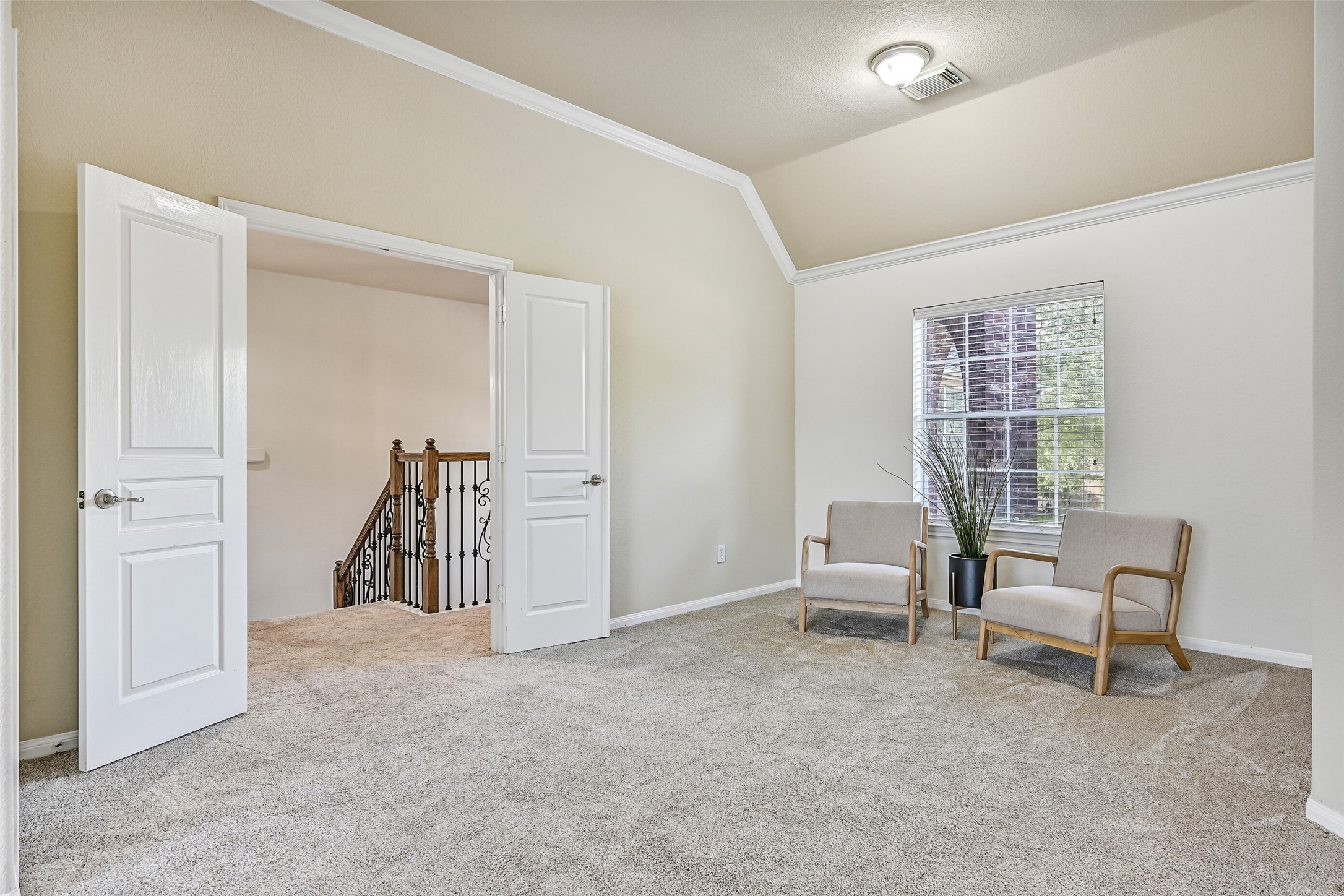 Double doors open into a truly impressive owner's retreat featuring fresh neutral paint, plush new carpet, crown molding, a lighted ceiling fan, and enough space for oversized furnishings with room to spare. The unique layout creates a private and peaceful atmosphere that feels more like a luxury suite than a traditional bedroom.