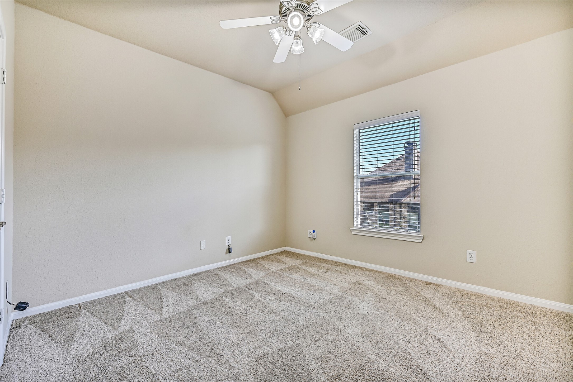 This generously sized secondary bedroom is the first of three bedrooms located on the second floor. Features include fresh neutral paint, plush new carpet, an elevated gambrel ceiling accented by a lighted ceiling fan, a step-in closet, and a side-facing window with 2-inch blinds that brings in abundant natural light.