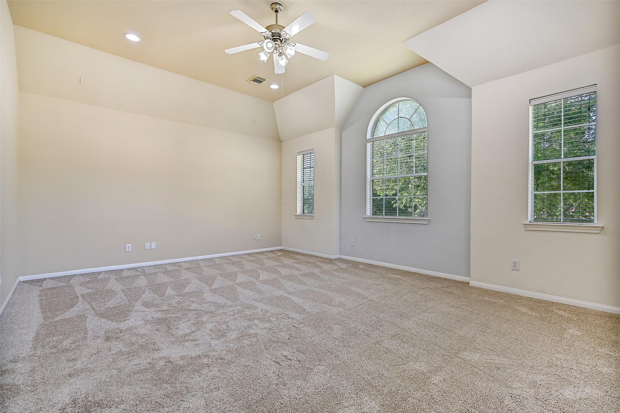 From this angle, the impressive scale of the game room is on full display. Multiple windows, including a striking arched window, fill the space with natural light, while the vaulted ceiling enhances the open feel. Whether you envision a pool table, home theater, fitness area, or playroom, there's room here for it all.