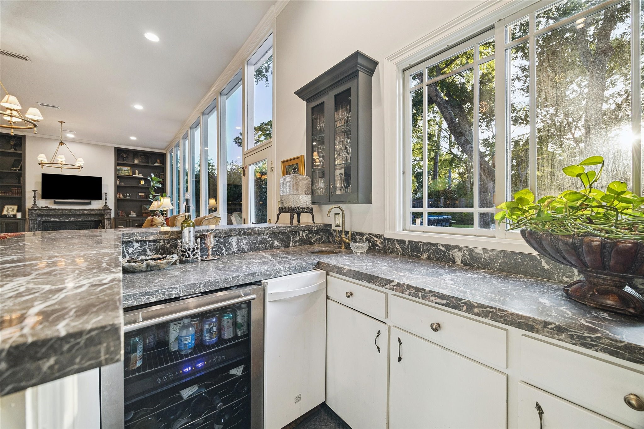 The wet bar features a serving window, ice maker and wine refrigerator.