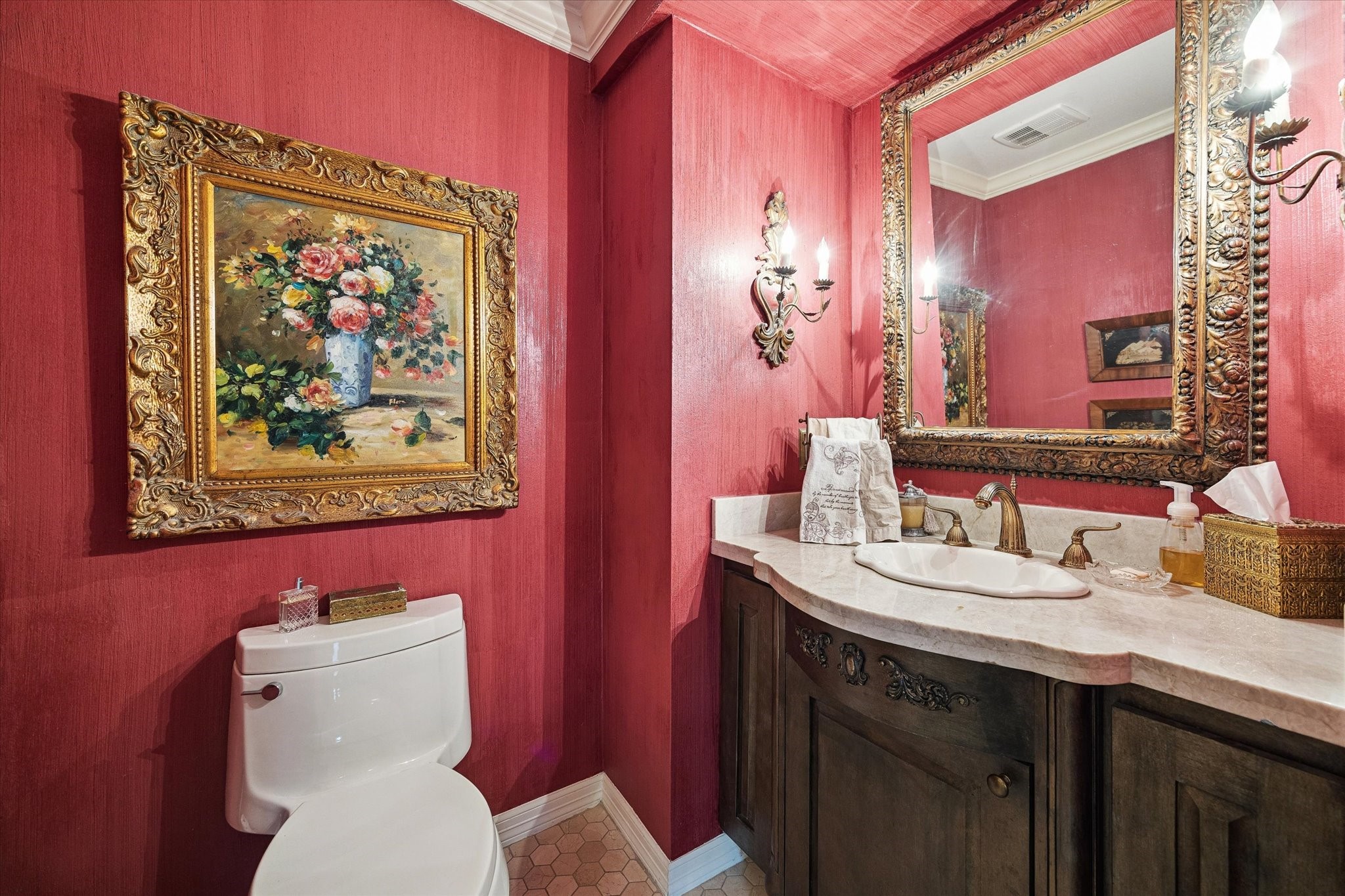 A fun powder bath, featuring rich red walls and ornate gold accents that exude timeless charm.