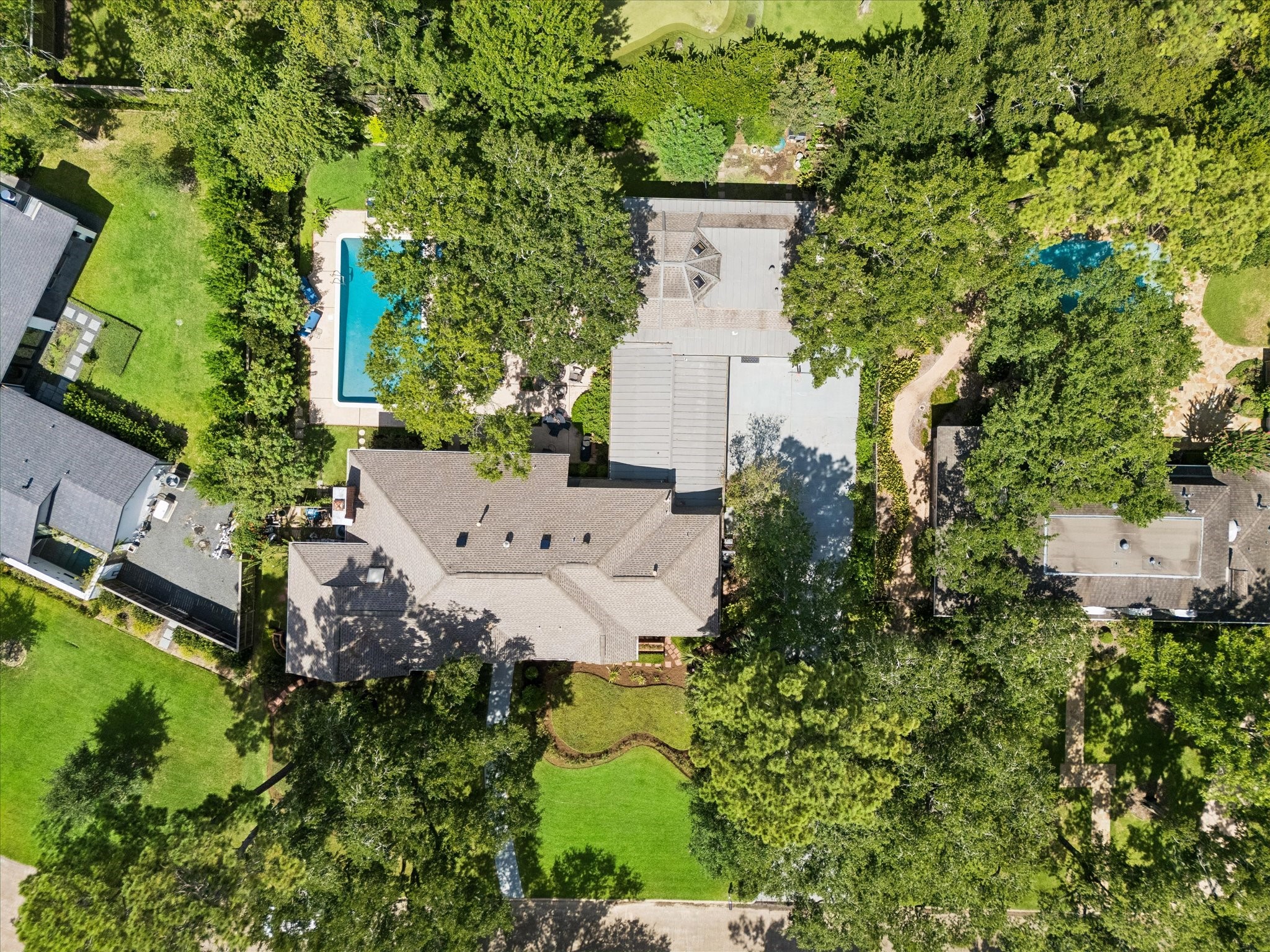 Sprawling estate nestled among lush greenery, featuring a large backyard with a sparkling swimming pool and ample outdoor space for relaxation and entertainment.