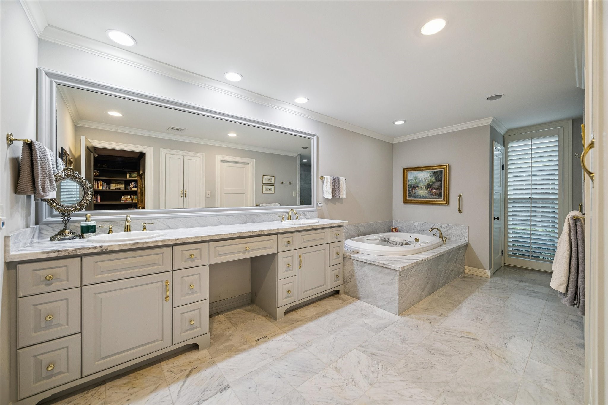 An elegant primary bathroom featuring a spacious double vanity, a relaxing whirlpool tub, and exquisite marble flooring, all bathed in soft, ambient lighting.
