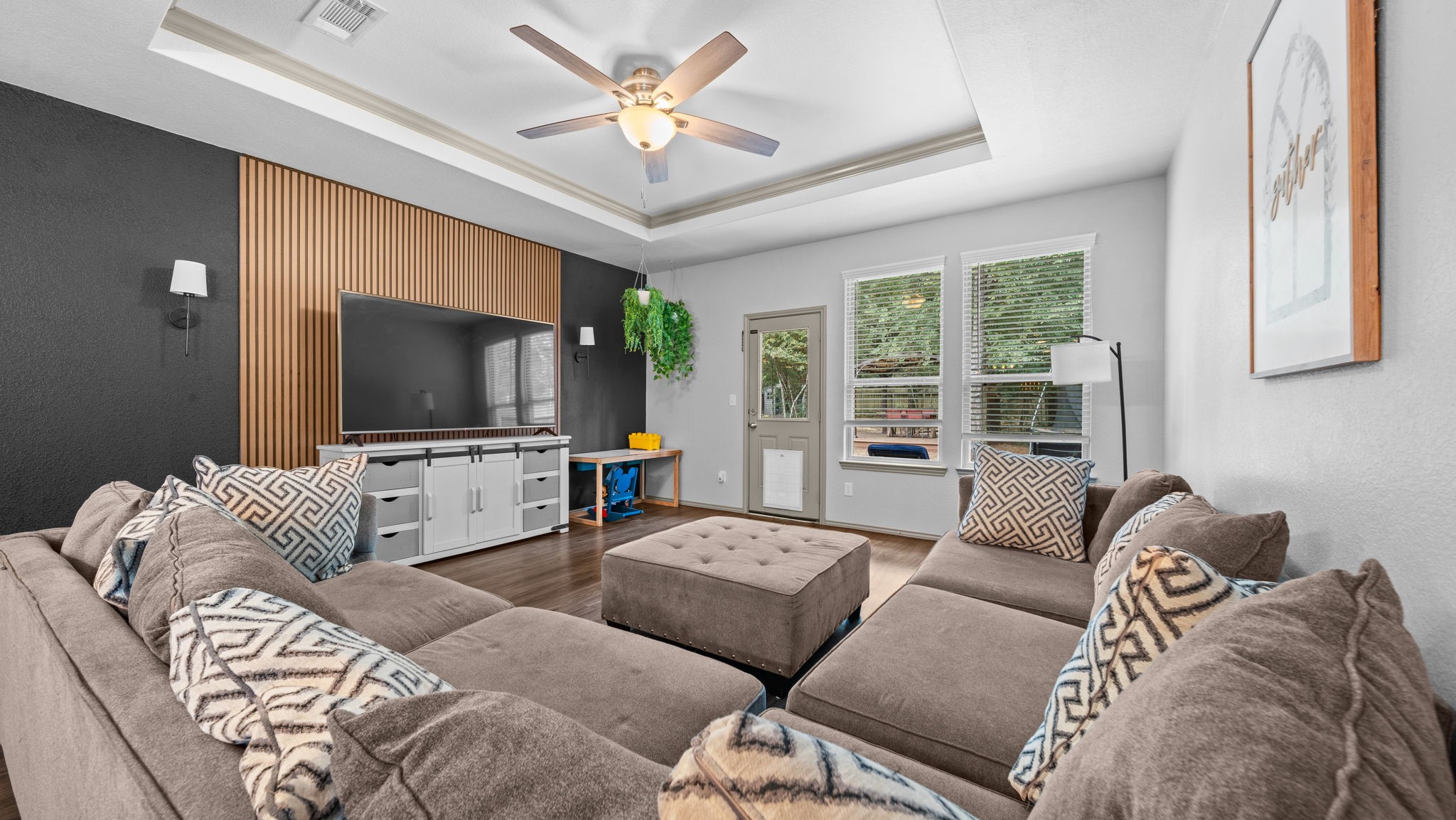 Fall in love with this inviting living room! A recessed tray ceiling and stunning specialty wood-slat accent wall create a stylish space to relax or entertain.Enjoy convenient backyard access through the living room, complete with a dog door that staysan added bonus for your four-legged companion! Fall in love with this inviting living room! A recessed tray ceiling and stunning specialty wood-slat accent wall create a stylish space to relax or entertain.Enjoy convenient backyard access through the living room, complete with a dog door that staysan added bonus for your four-legged companion!