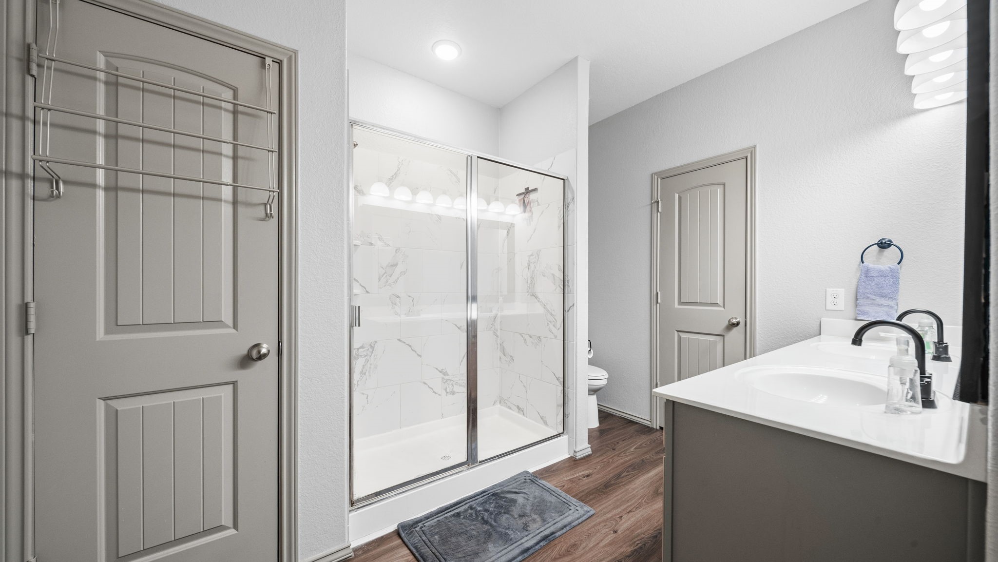 Your private retreat! The main primary bathroom features a spacious walk-in shower with beautiful marble-look tile and a modern vanity.