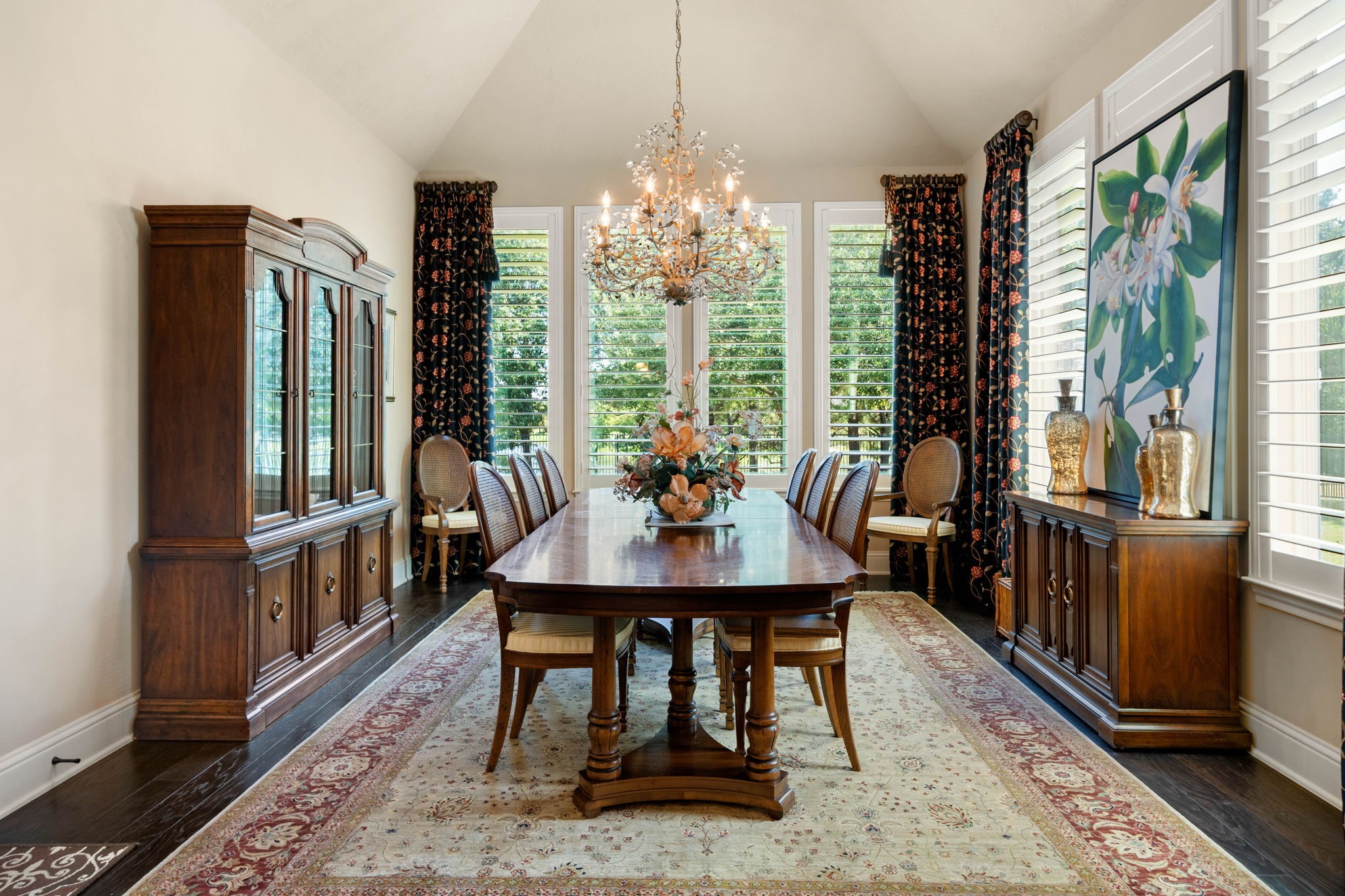 The formal dining area features a vaulted ceiling, shutters, and a statement chandelier for elegant entertaining.