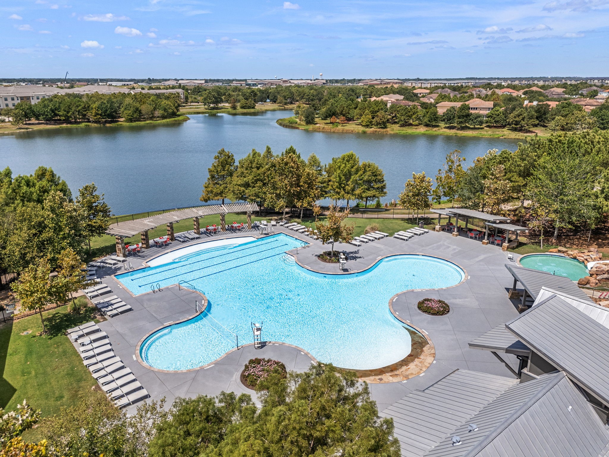 Adventure Island Waterpark in Cross Creek Ranch in Fulshear features an expansive resort-style pool with dedicated lap lanes, tanning shelves with water jets, a wading pool, and an iconic 140-foot waterslide, all set beside a scenic community lake.