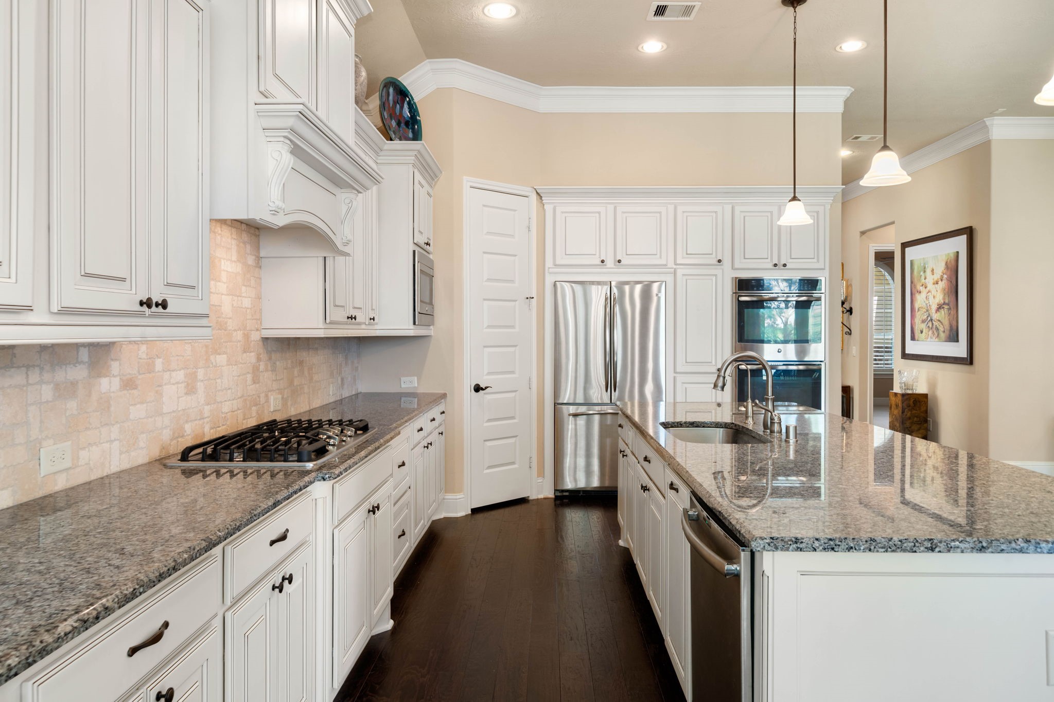 Soft-close cabinetry, a stone backsplash, and a gas cooktop bring both style and function to this well-appointed kitchen.