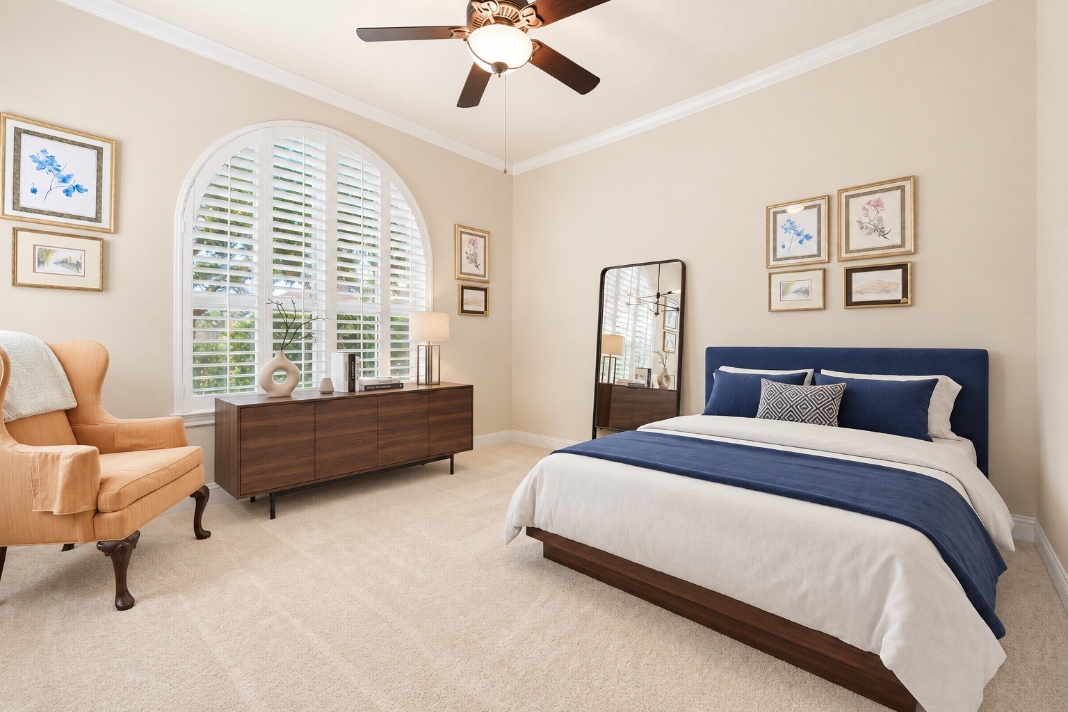 A secondary bedroom features an arched window with shutters, adding architectural charm and natural light. Virtually staged.