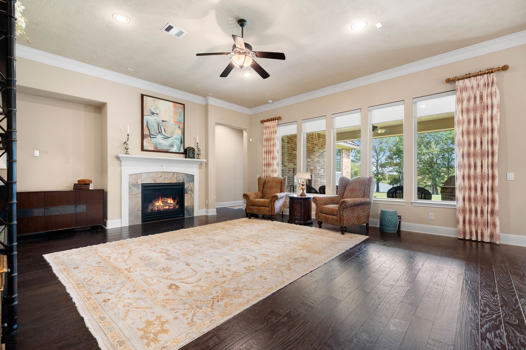 The living room centers around a cozy gas log fireplace, framed by high ceilings and a wall of windows that fill the space with natural light.