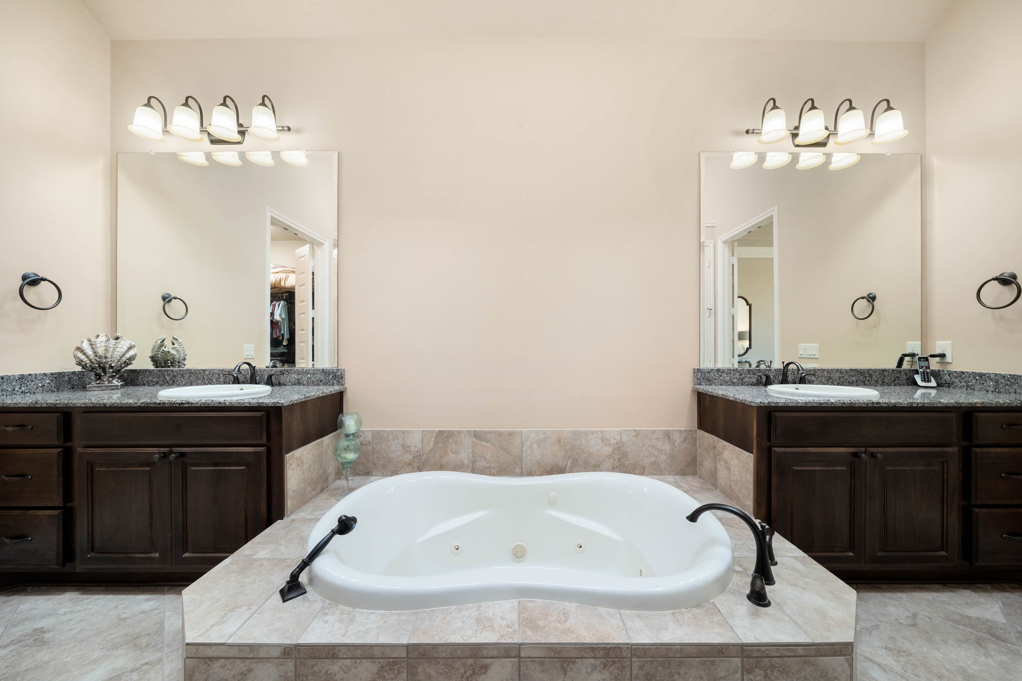 The primary bath offers a spa-like escape, featuring a jetted garden tub flanked by dual vanities with granite countertops.