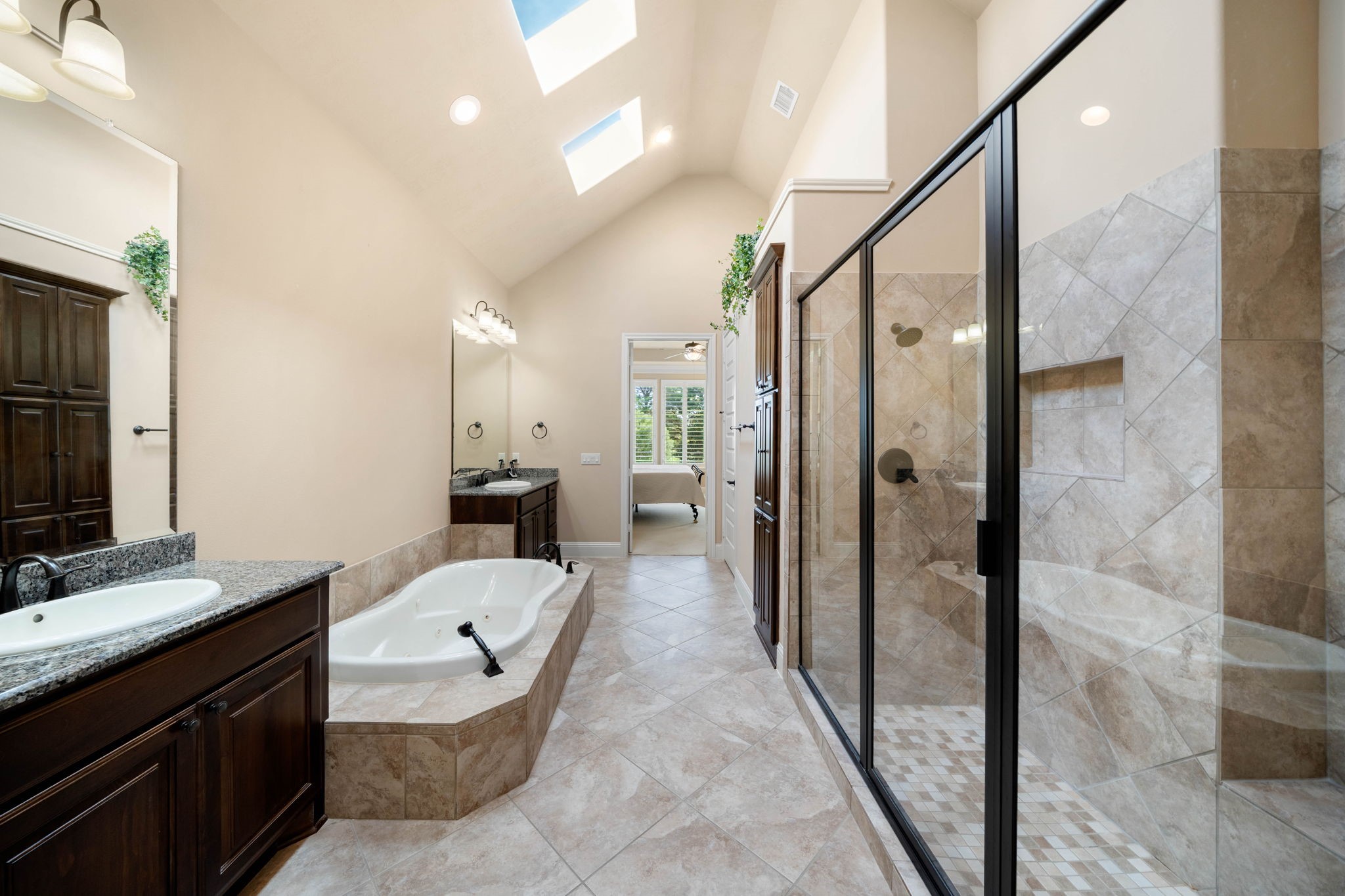 A separate walk-in shower and vaulted ceiling with skylights bring in natural light and add a sense of openness to the primary bath.