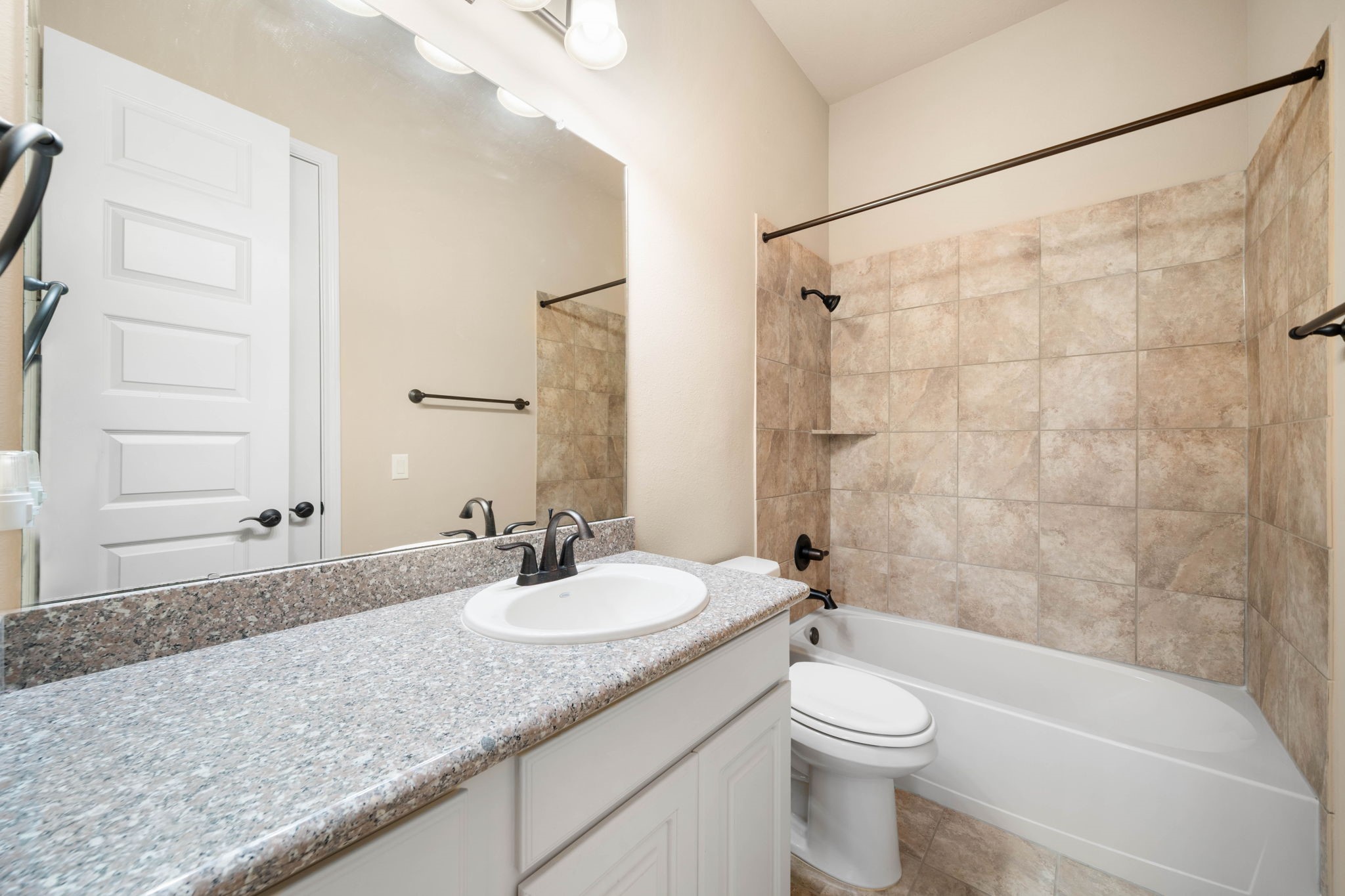 The secondary bathroom features granite countertops and a tub/shower combo finished with tile surround.
