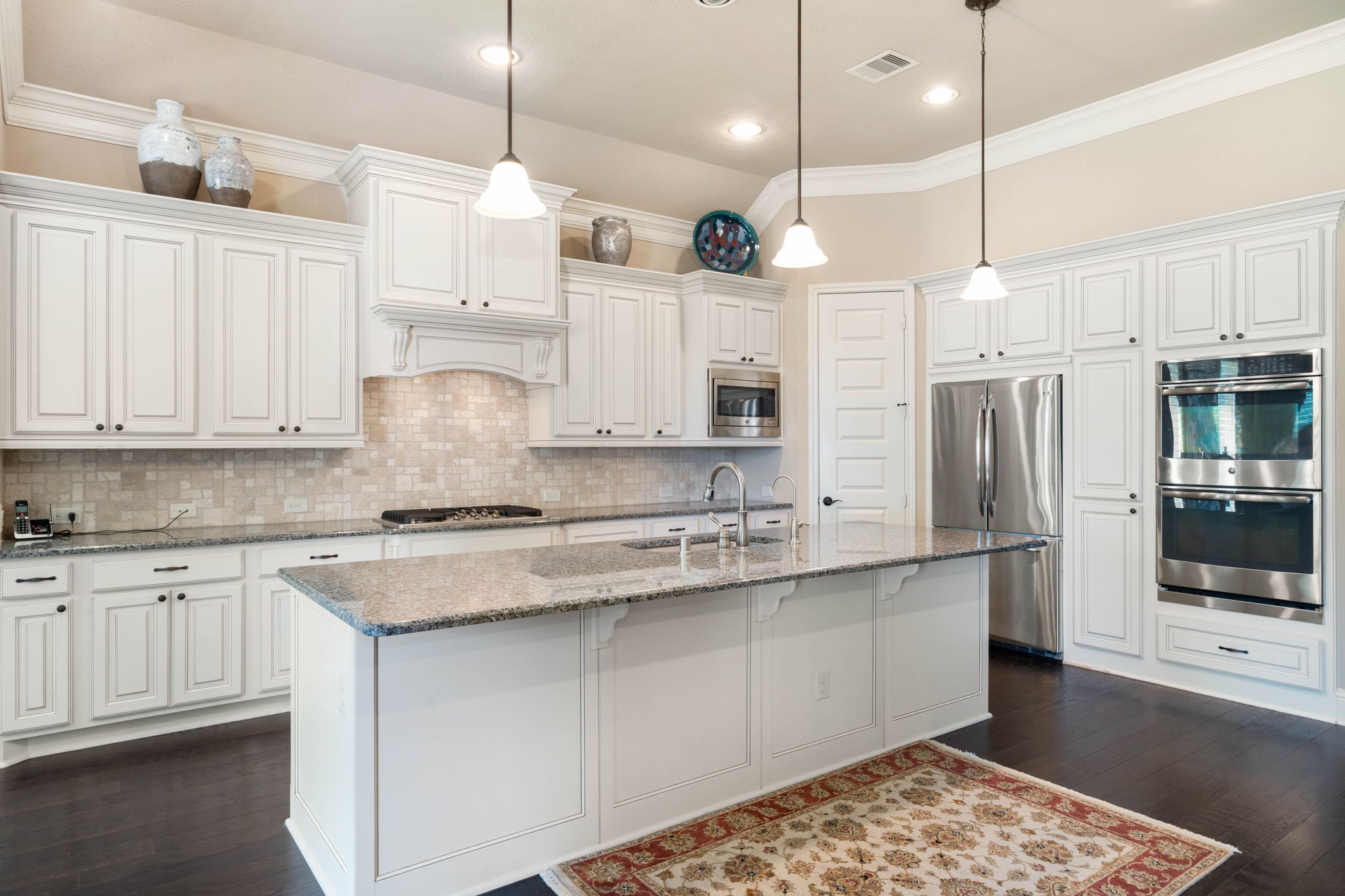 The kitchen is a showstopper, featuring granite countertops, a spacious island, and stainless steel double ovens.