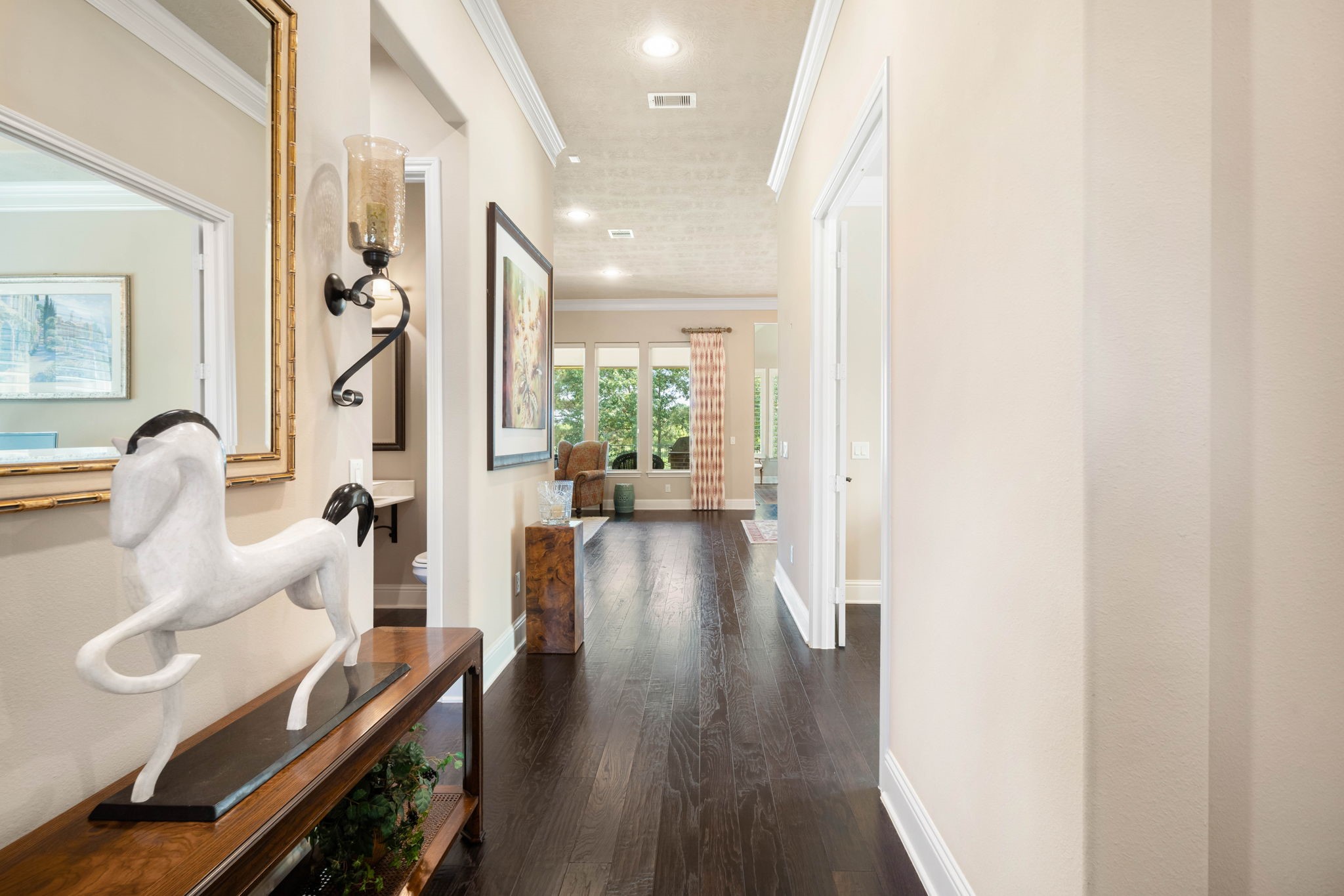The foyer welcomes you home with rich hardwood flooring, crown molding, and an open sightline into the main living space.