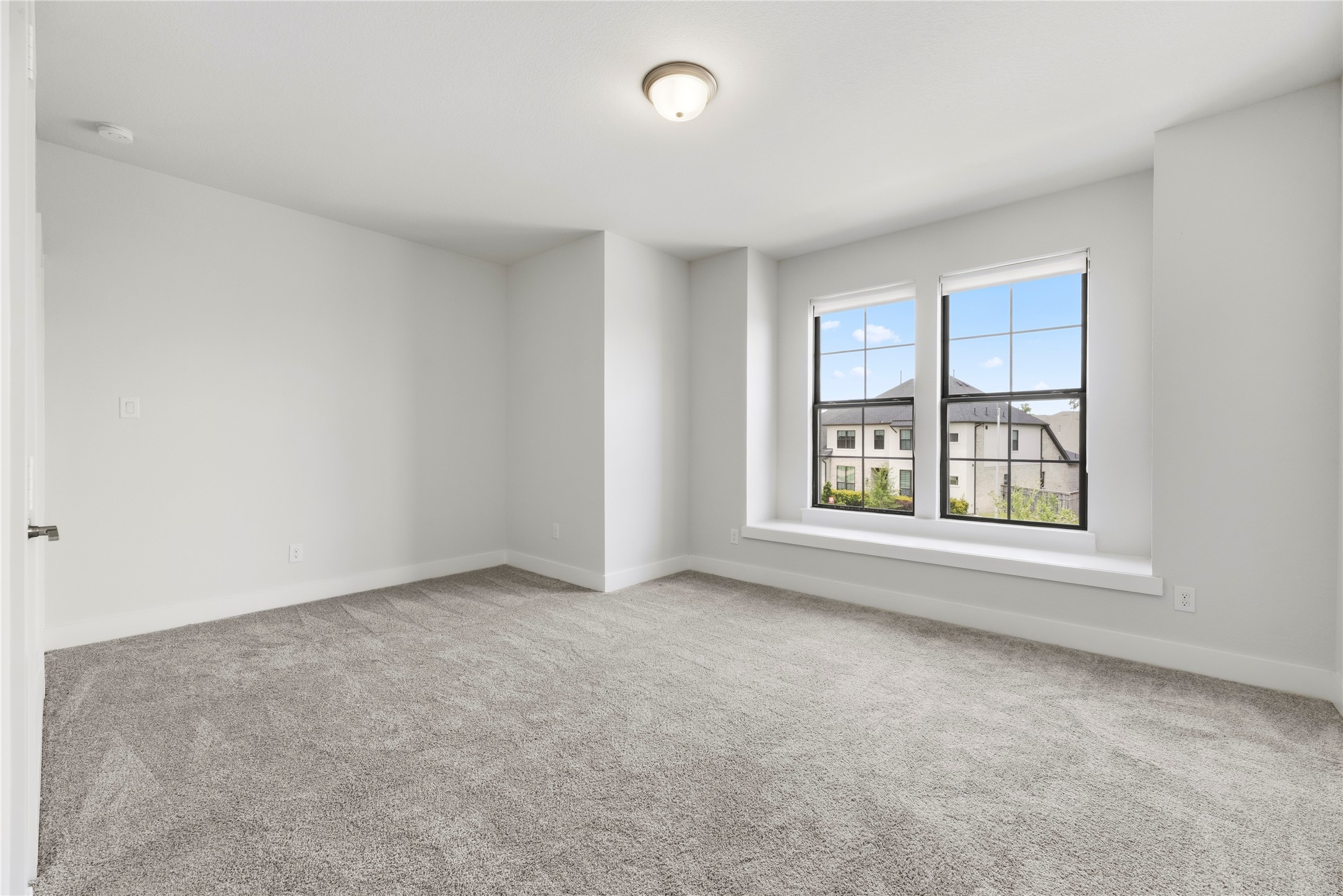 Spacious secondary bedroom featuring fresh carpet, neutral paint, and double windows with a charming built-in bench seat.