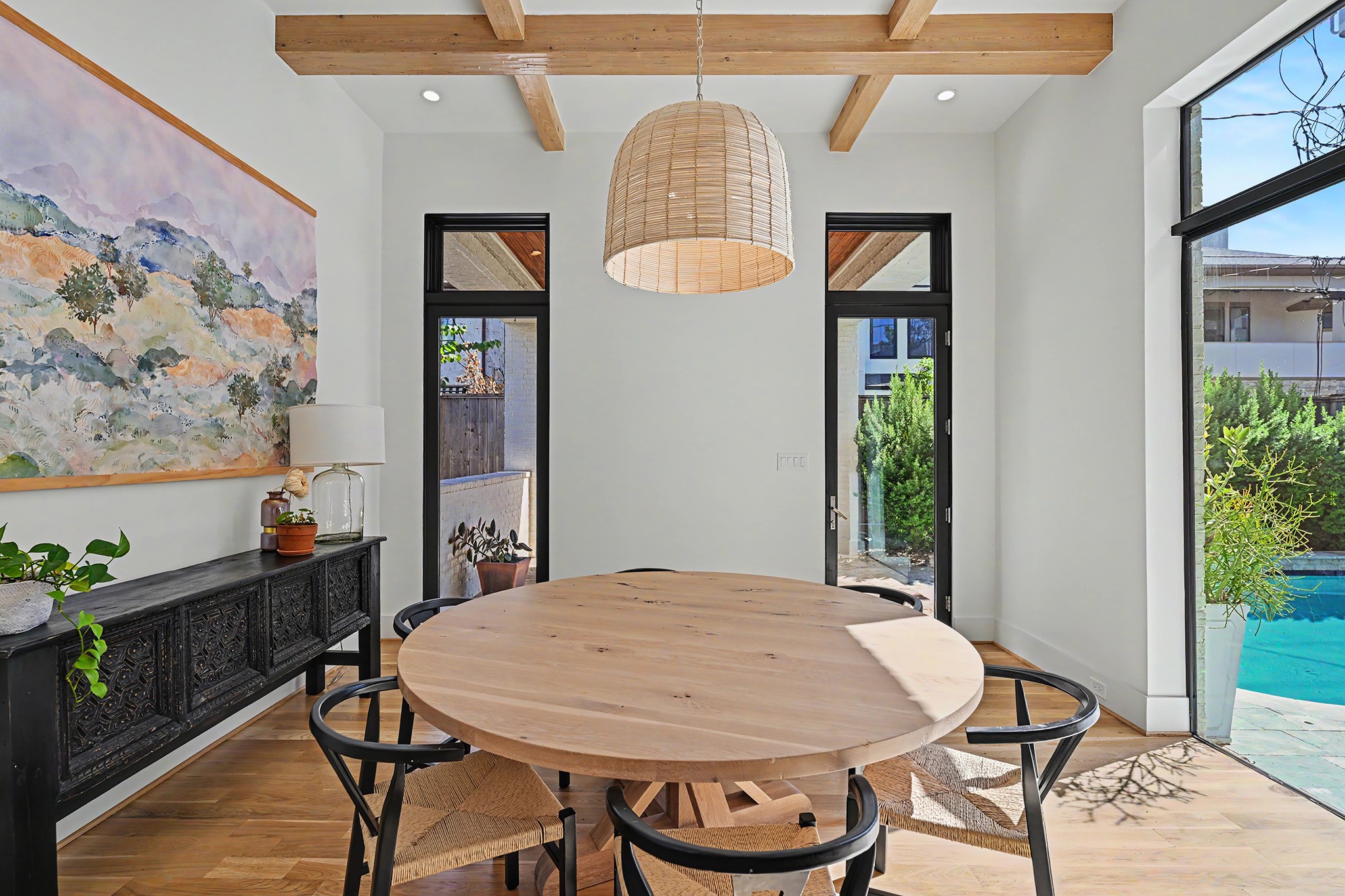 The dining room is illuminated by a woven fixture and opens directly to the pool.