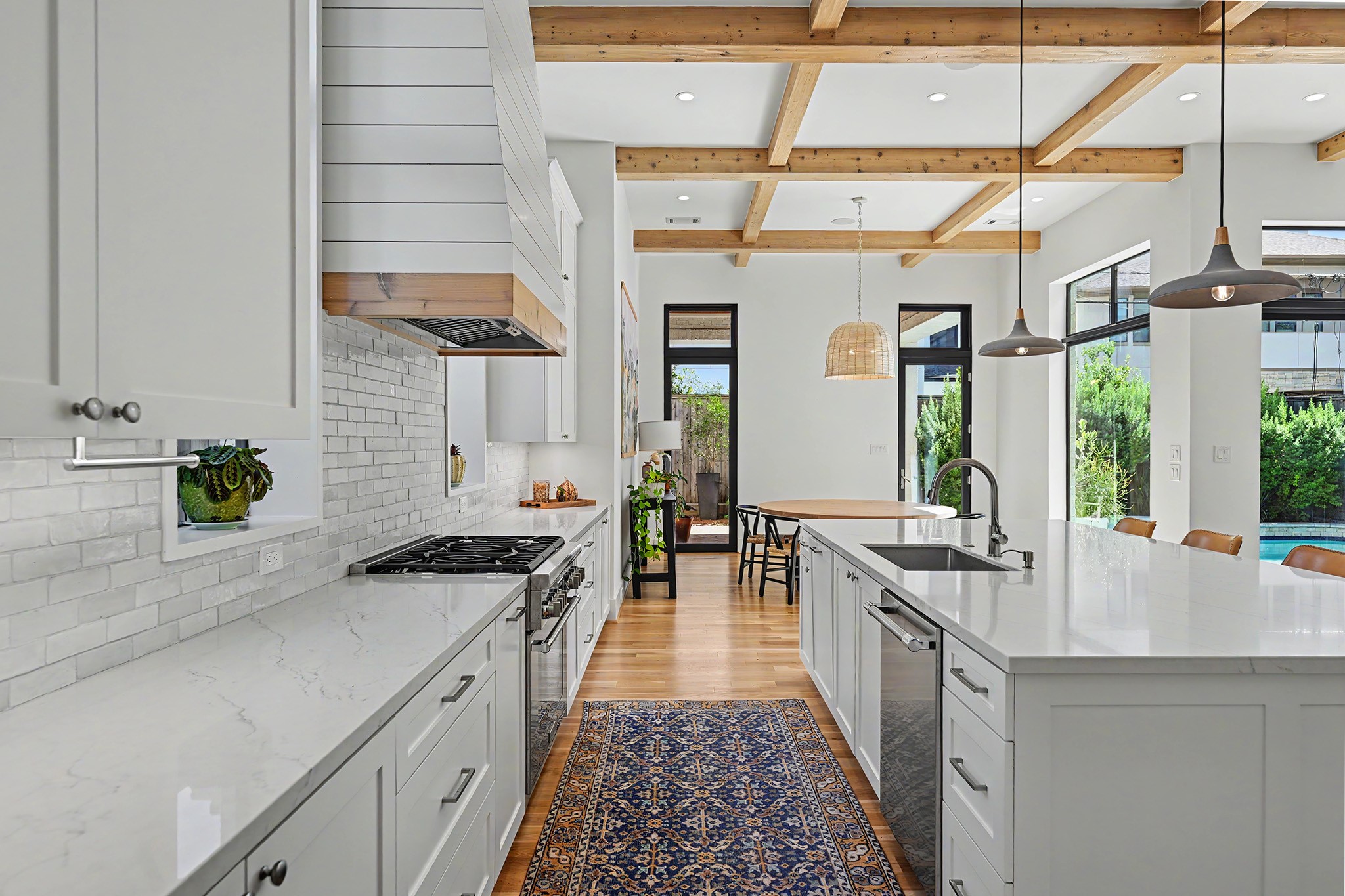 An additional kitchen view highlights the custom range hood, Riad tile backsplash and open flow between the principal living spaces.