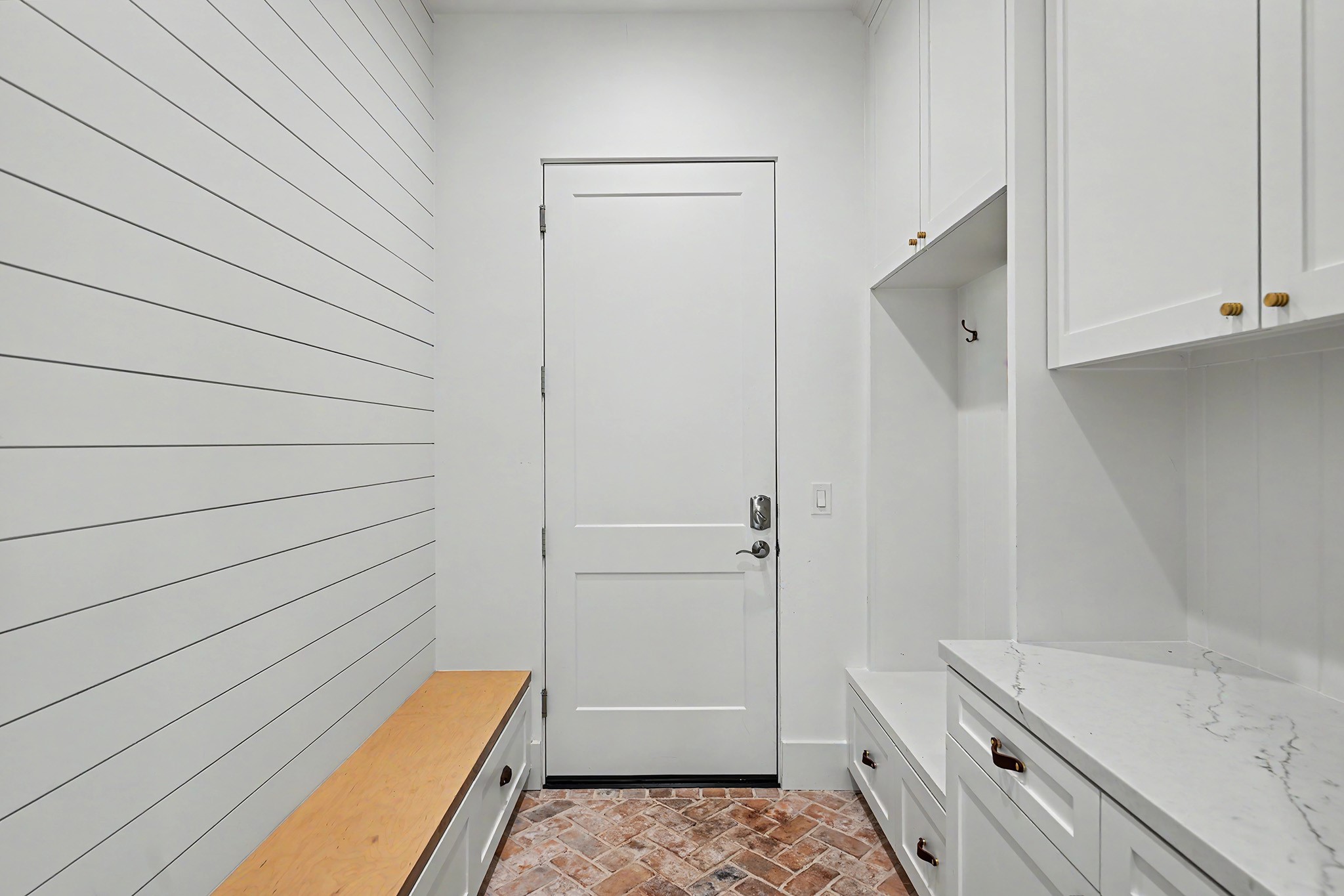 The thoughtfully designed mudroom offers built-in cabinetry, a bench and convenient everyday storage.