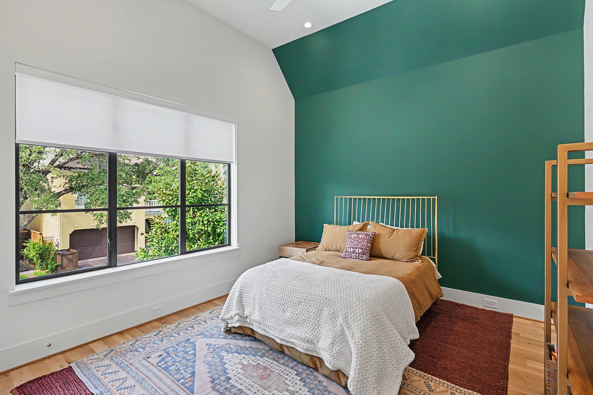 A striking accent wall and oversized window bring color and character to this secondary bedroom.
