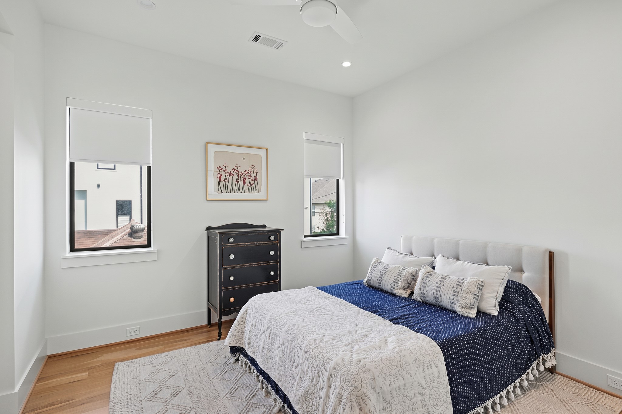 A bright secondary bedroom features white oak floors, high ceilings and abundant natural light.