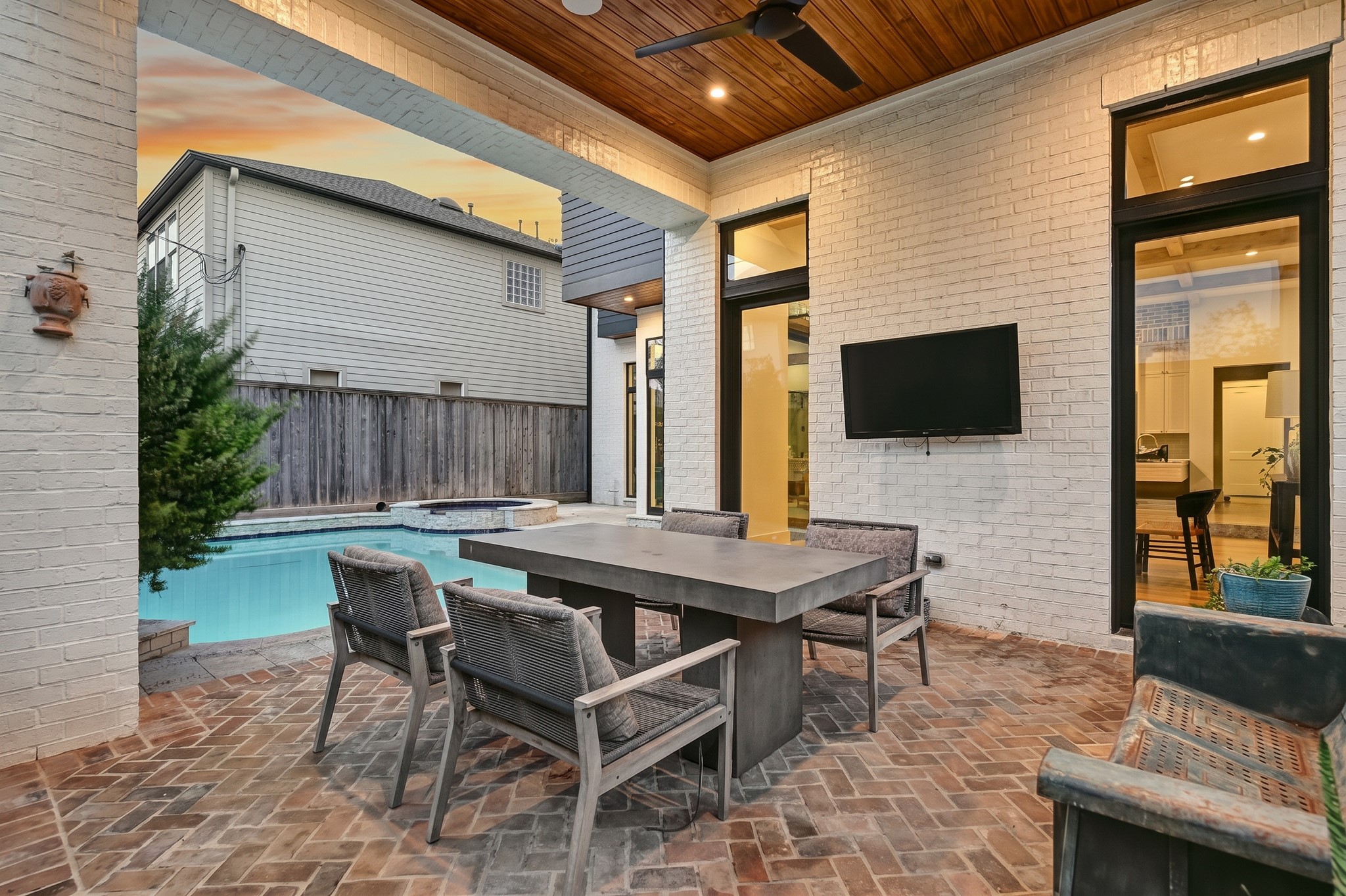 The covered patio features a warm wood ceiling and ample room for outdoor dining beside the pool.