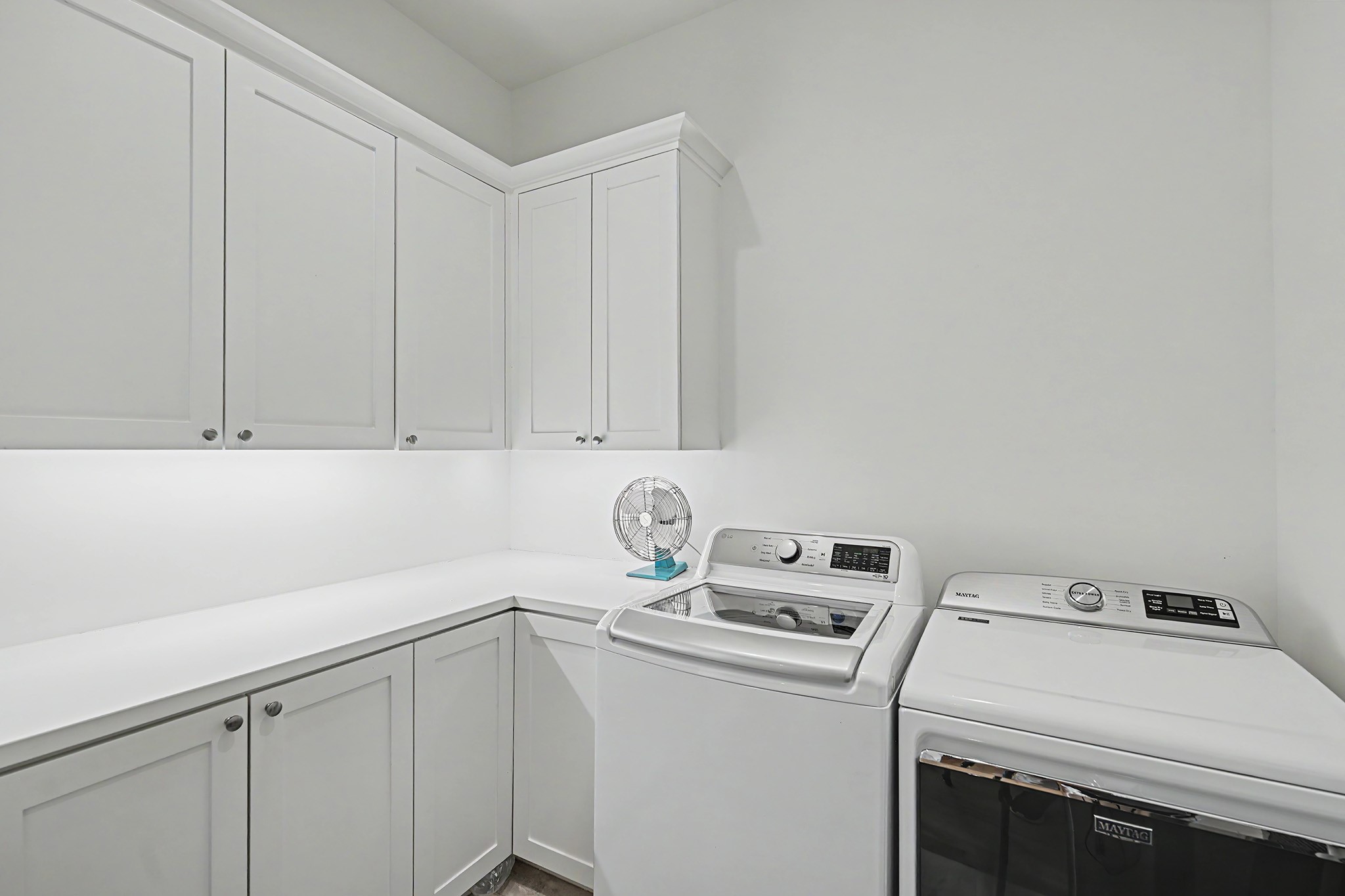 The utility room offers extensive cabinetry, generous workspace and refined finishes rarely found in a service space.