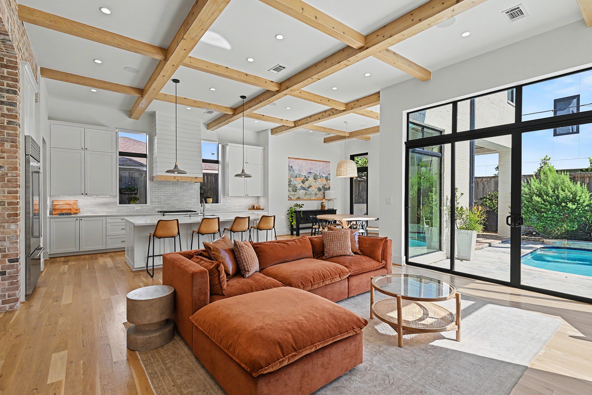 Cedar ceiling beams and expansive black-framed windows bring warmth and architectural presence to the open living area.