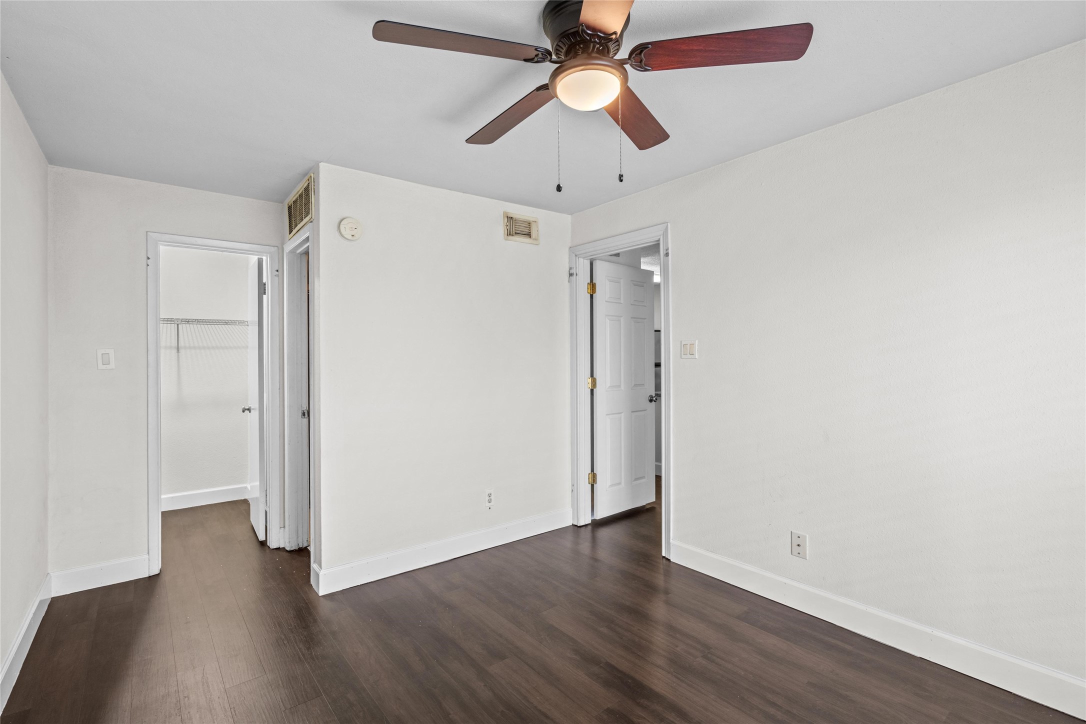 Well-sized bedroom features wood-look flooring, a ceiling fan, and natural light from the window