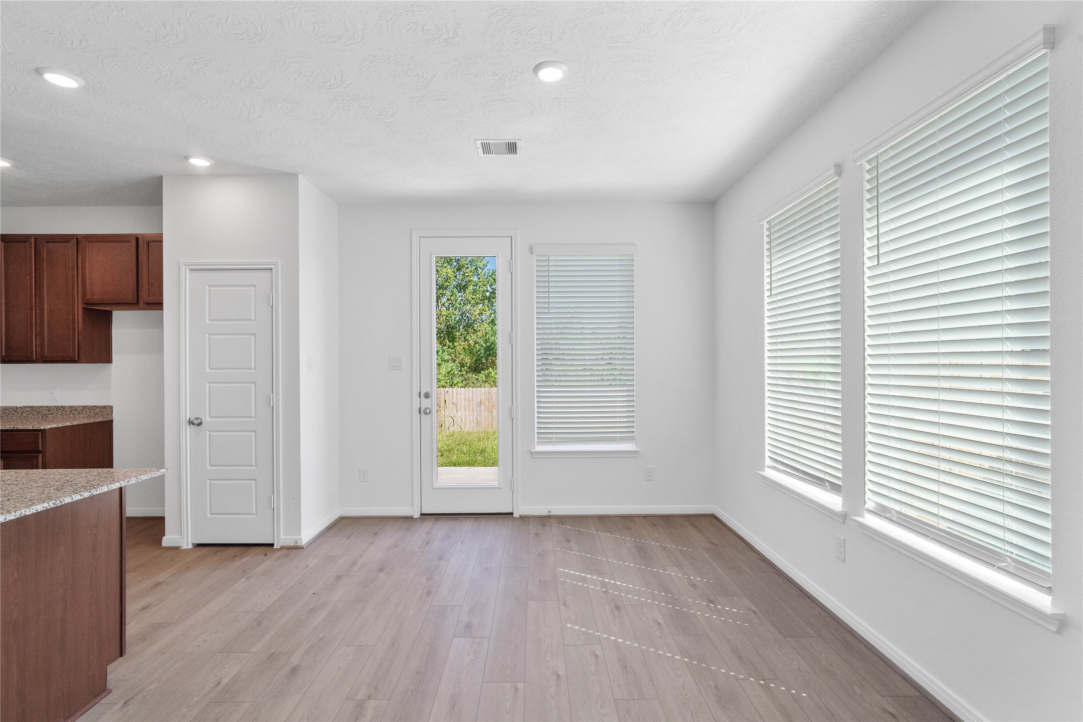Start your day with a warm cup of coffee and quality time in this charming dining area! Highlights include large windows with blinds, custom neutral paint, vinyl plank flooring, recessed lighting, high ceilings, and a convenient door leading to the rear patio and backyard.