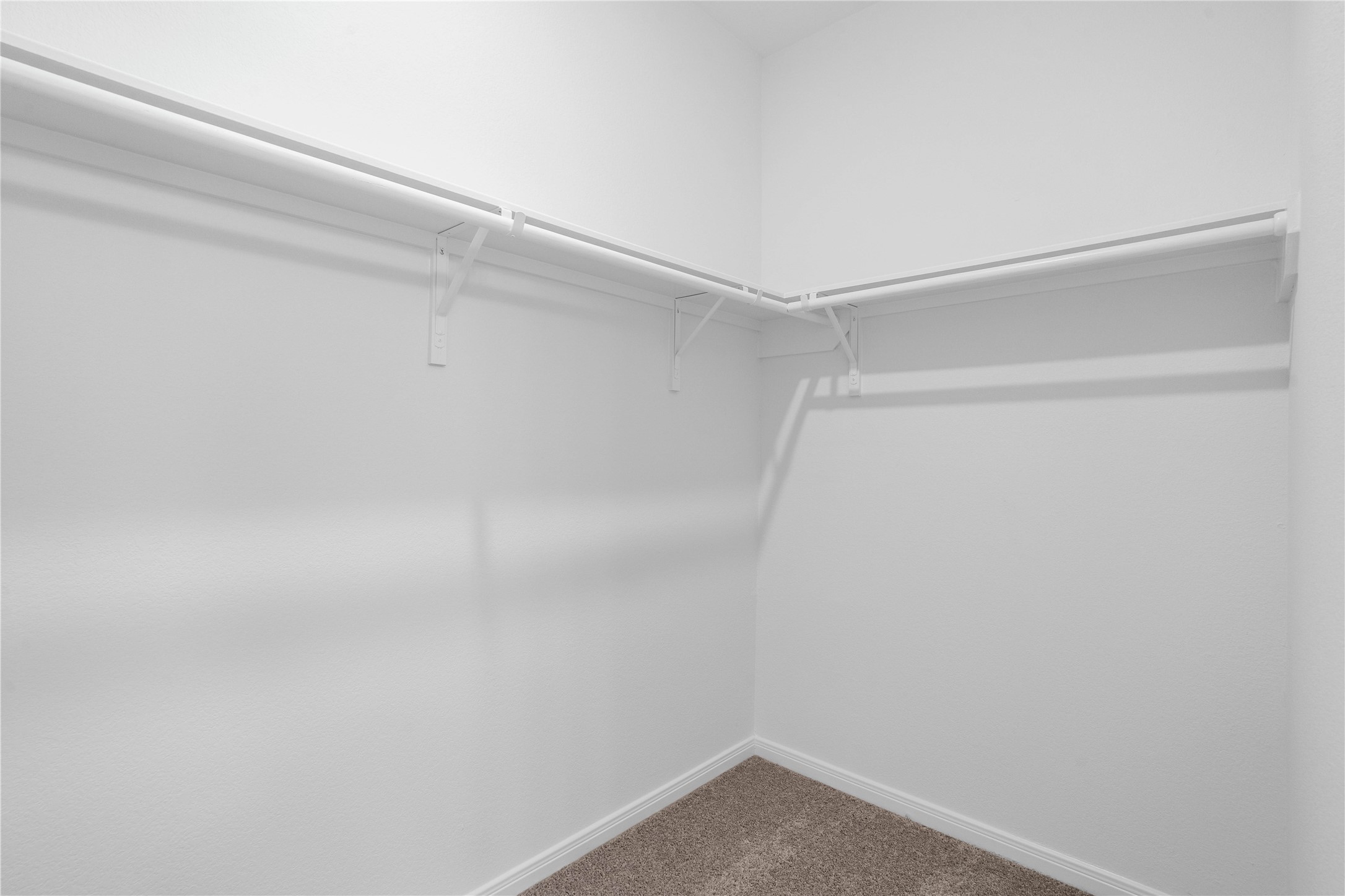 Spacious primary walk-in closet featuring functional built-in shelving and ample hanging space.