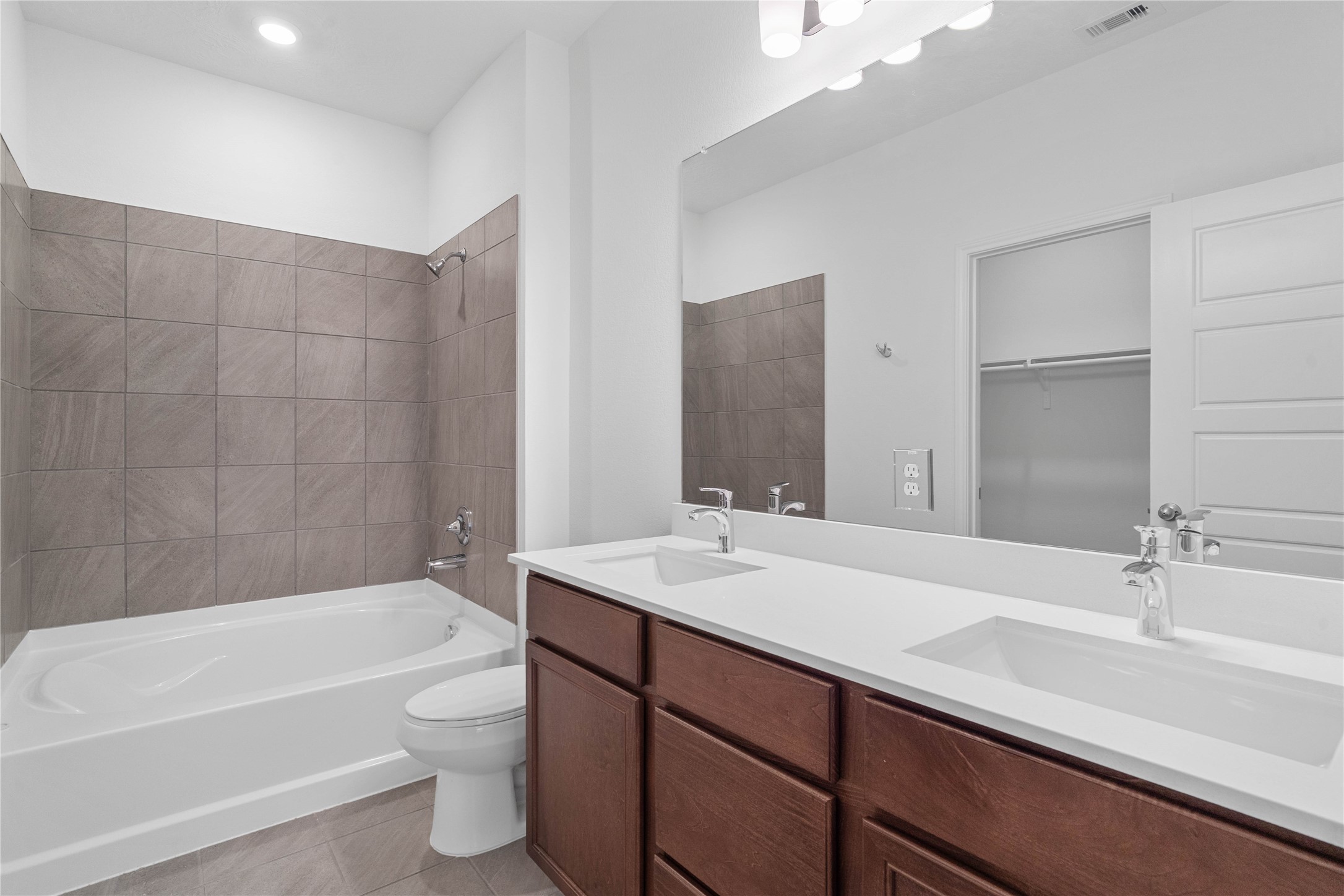 This beautifully updated primary bathroom is move-in ready! It showcases stained cabinetry paired with light countertops, dual vanity sinks, a large mirror, spacious walk-in closet with built-in shelving, high ceilings, custom paint, and stylish modern finishes throughout.