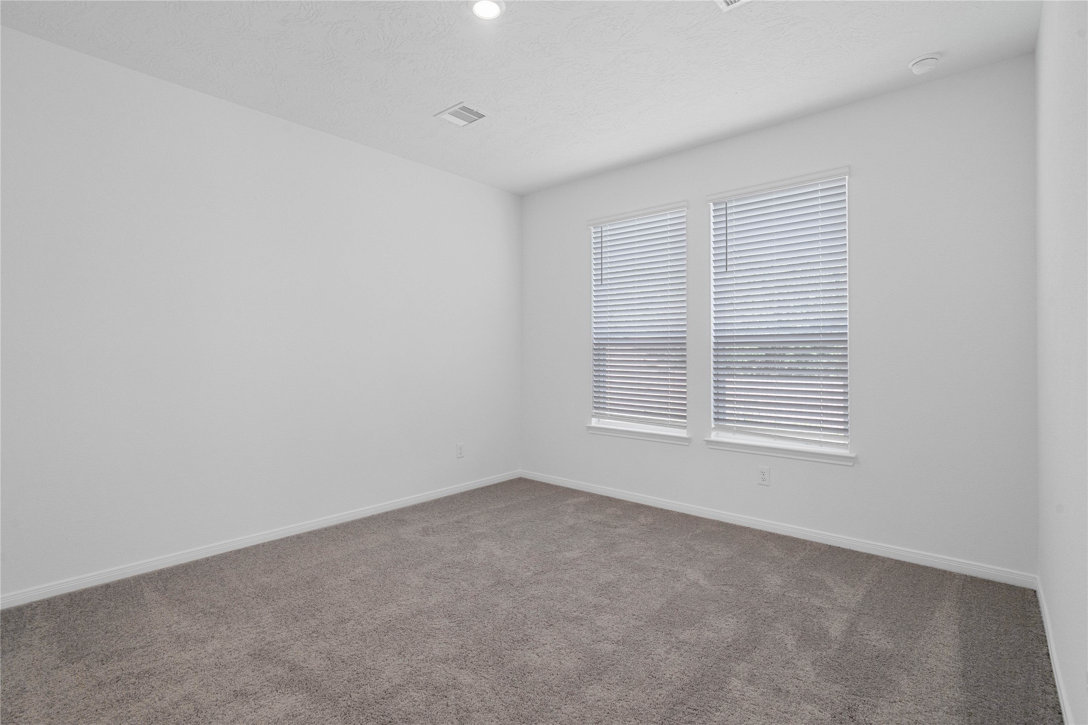 Unwind after a long day in this stunning primary suite! This spacious retreat features plush carpeting, neutral-toned walls, high ceilings, recessed lighting, and large windows with privacy blinds for comfort and tranquility.