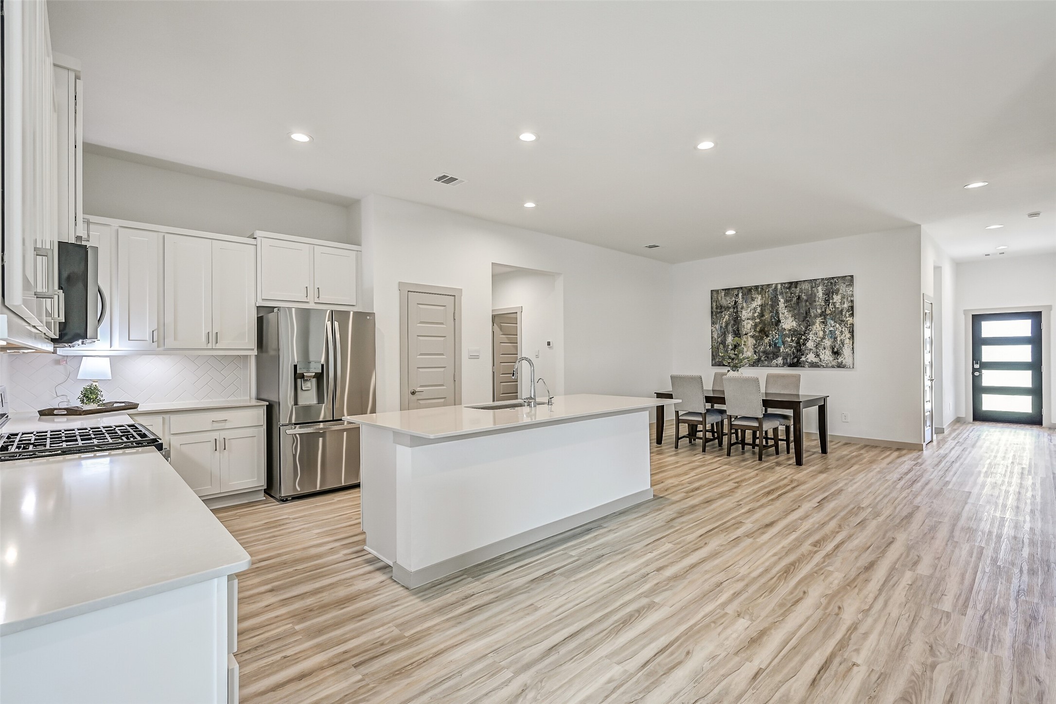 The heart of the home is an impressive open-concept kitchen & dining space with an oversized island, abundant cabinetry, stainless appliances and continuous wood-look flooring that creates a seamless flow throughout the main living areas.