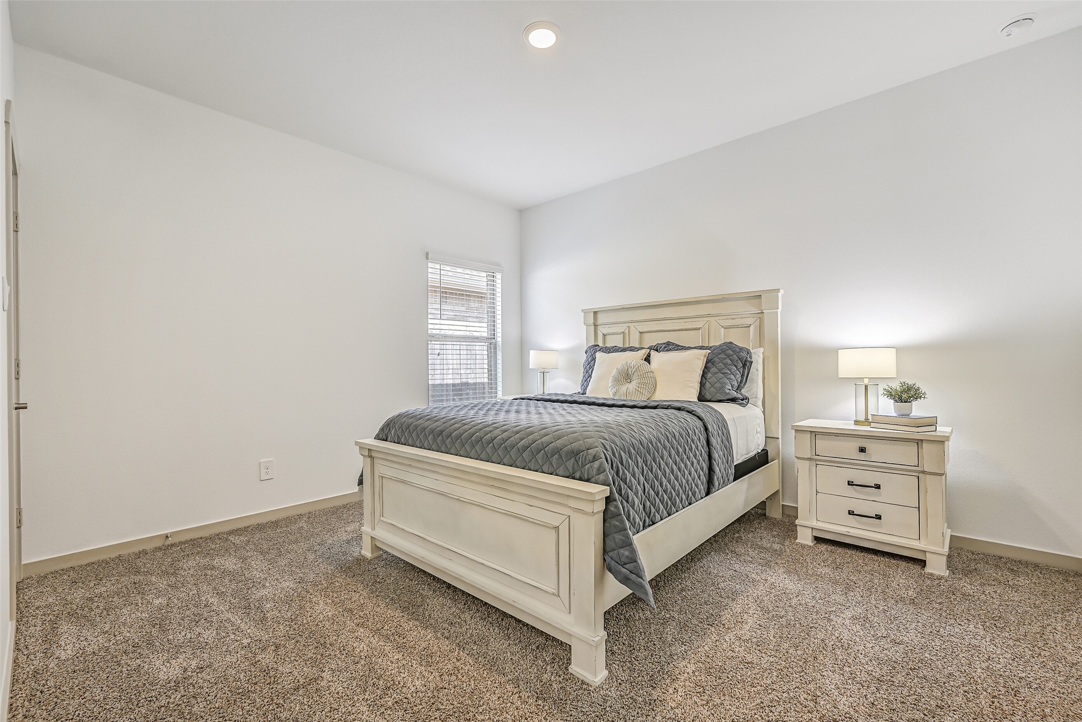 A generously sized secondary bedroom continues the home's light, neutral palette with plush carpet, tall ceilings and a large window providing plenty of natural light.