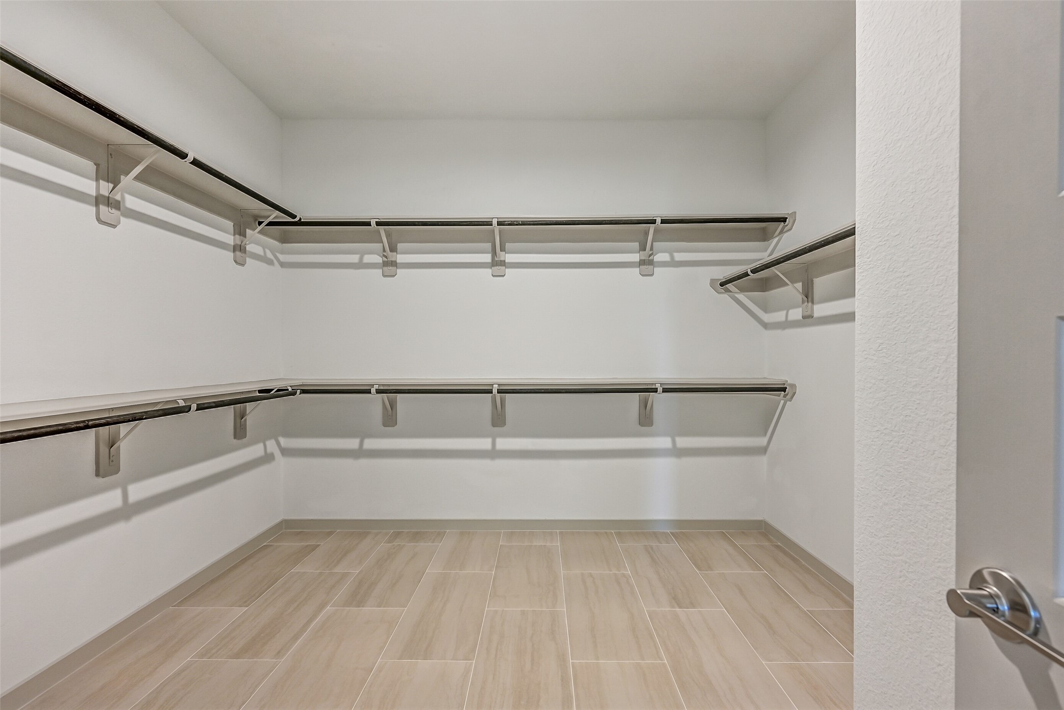 The generous primary walk-in closet provides extensive double-tier hanging and shelf space on multiple walls, along with easy-care tile flooring for exceptional storage and organization.