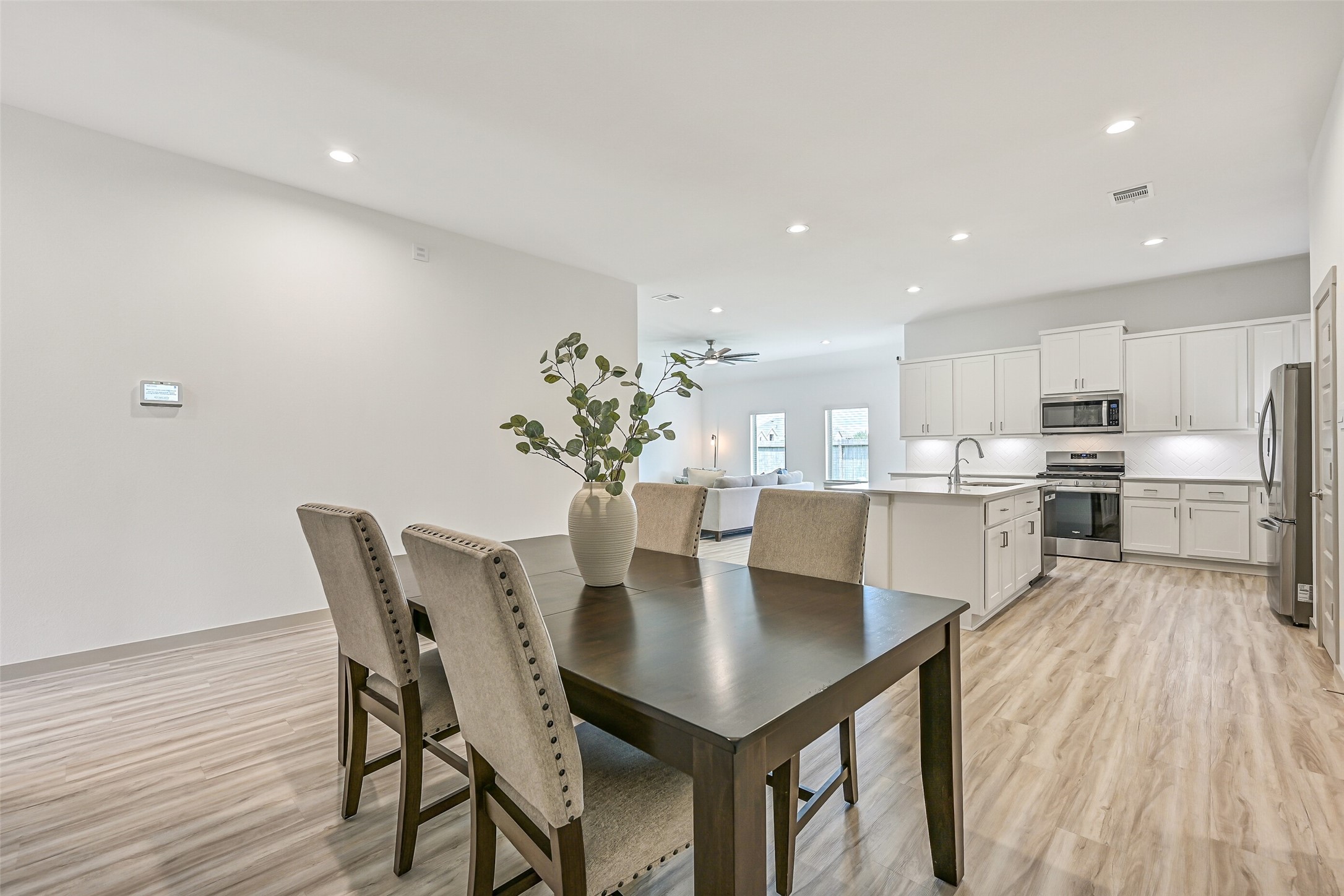 From the dining area, enjoy wide-open sightlines into the kitchen and family room. Recessed lighting and continuous wood-look flooring enhance the bright, airy feel of this thoughtfully designed open floor plan.