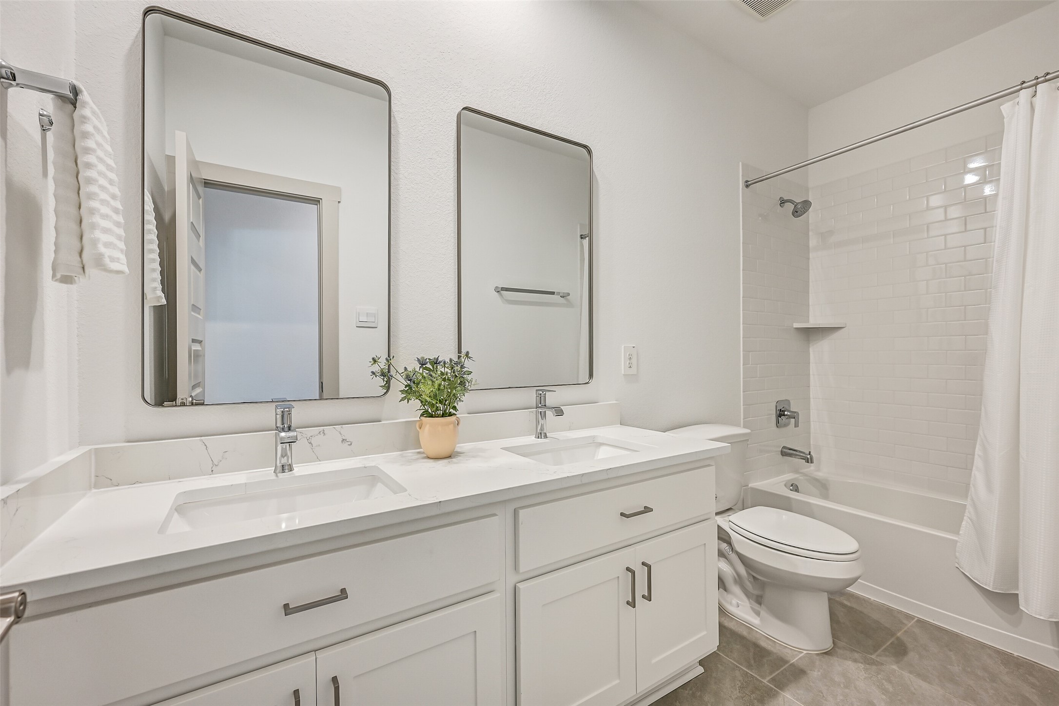 The secondary bath offers plenty of space to share with dual undermount sinks, generous vanity storage, sleek fixtures and a tiled tub/shower combination.