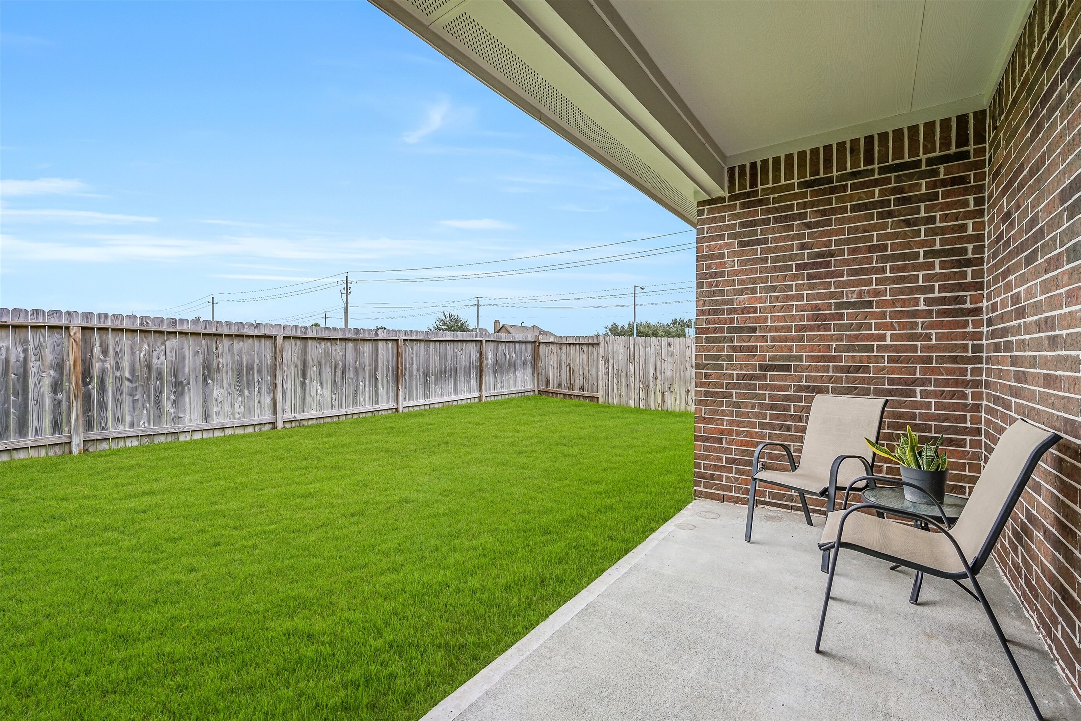 Step outside to the covered rear patio overlooking the spacious fenced backyard, offering a shaded spot for outdoor dining, morning coffee or simply relaxing while enjoying the green space beyond.