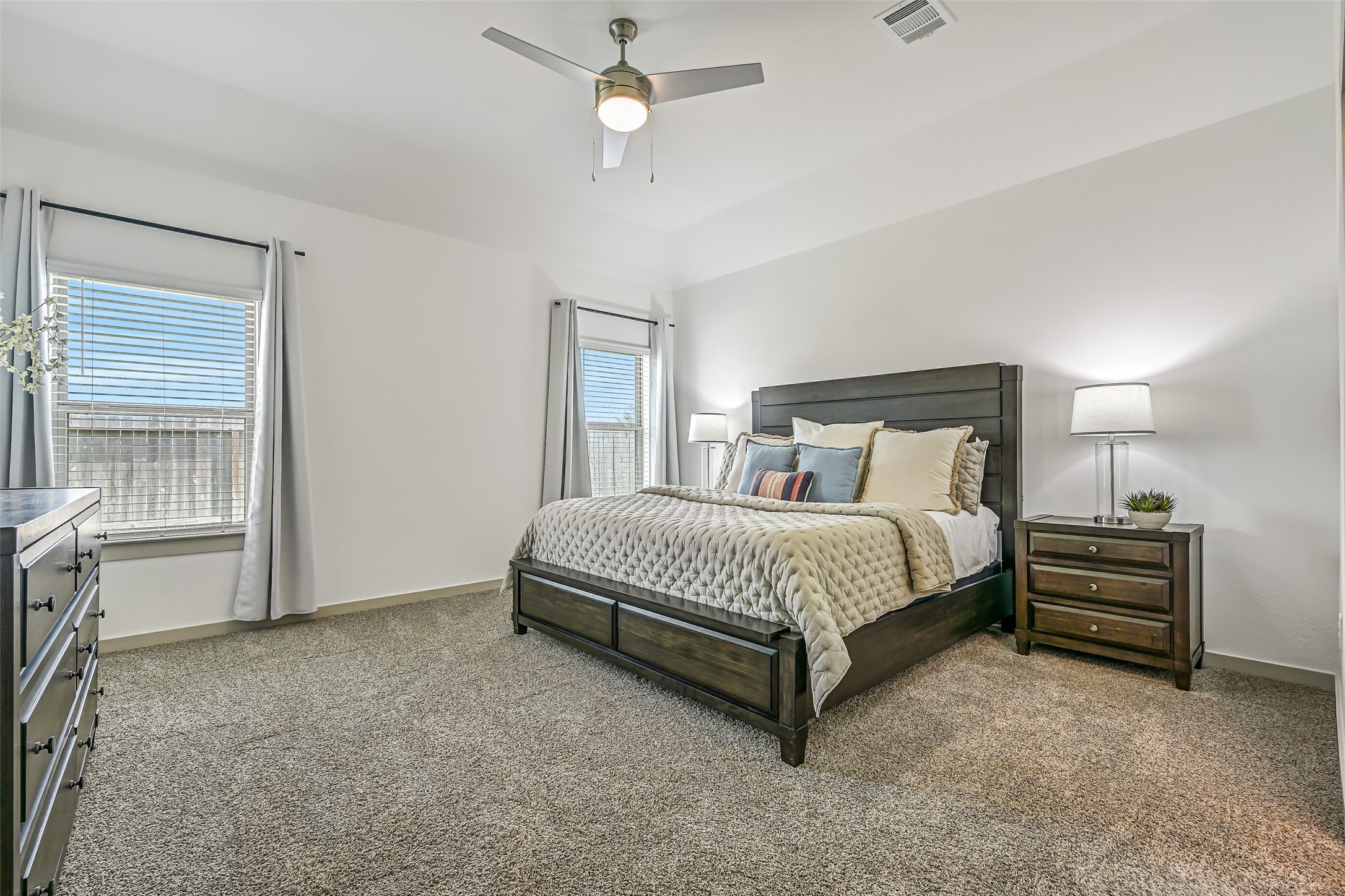 The spacious and secluded primary retreat offers a gambrel ceiling with ceiling fan, plush neutral carpet and multiple windows providing abundant natural light, with plenty of room for a full complement of bedroom furnishings.