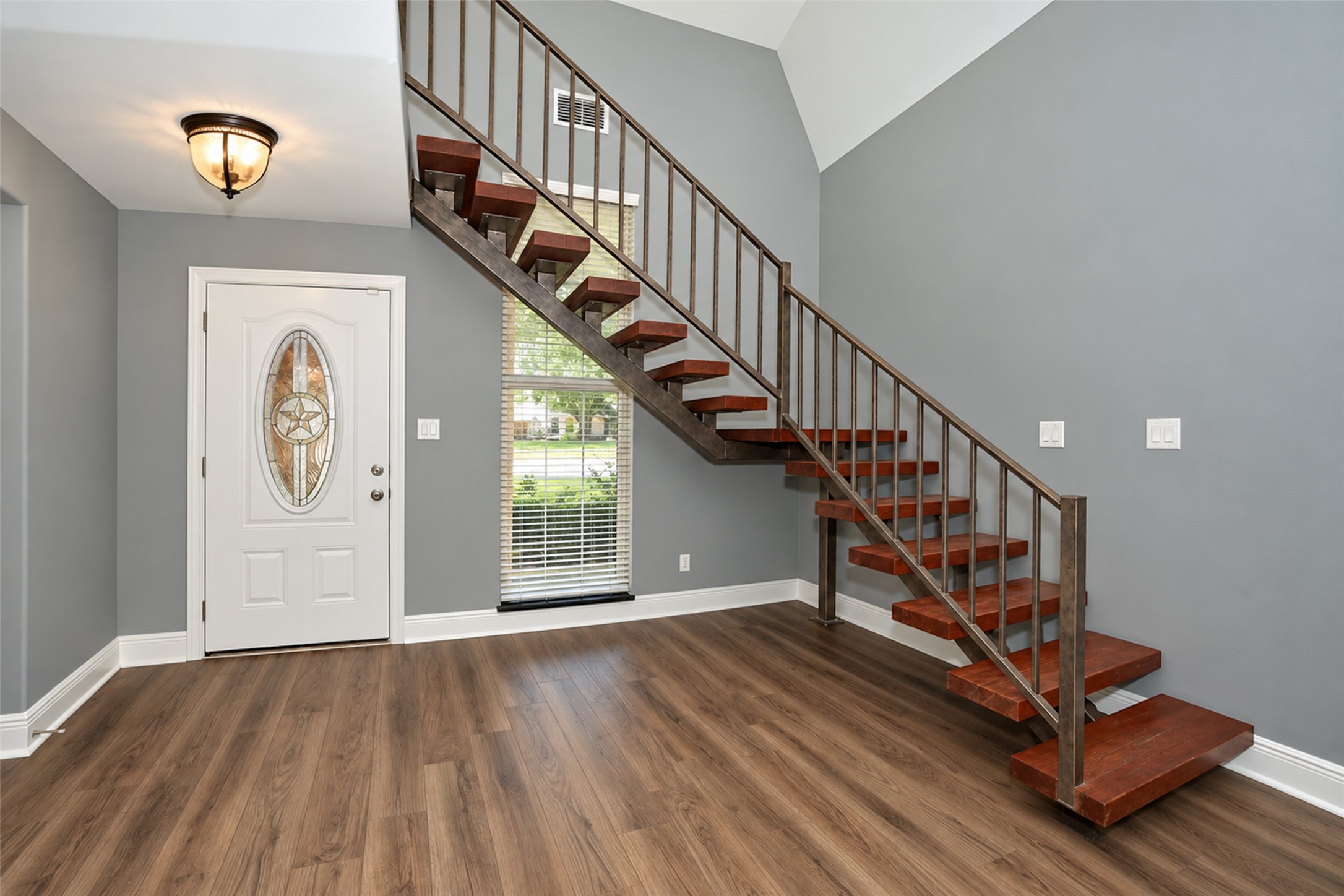 Custom wooden stairs and a striking metal stair rail crafted from reclaimed materials salvaged from a historic downtown Houston building, adding unique character and a one-of-a-kind touch to the home.